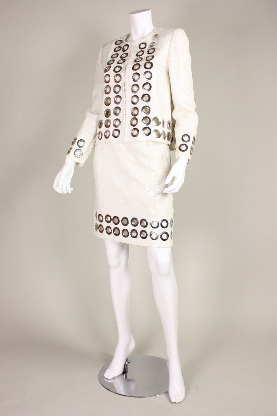 Vintage three piece ensemble from Jeanette Kastenberg for St. Martin dates to the 1980's.  It is covered with white sequins and has large silver-toned grommets, which trim the jacket and skirt.  Jacket has center front hook and eye closures.  Tank