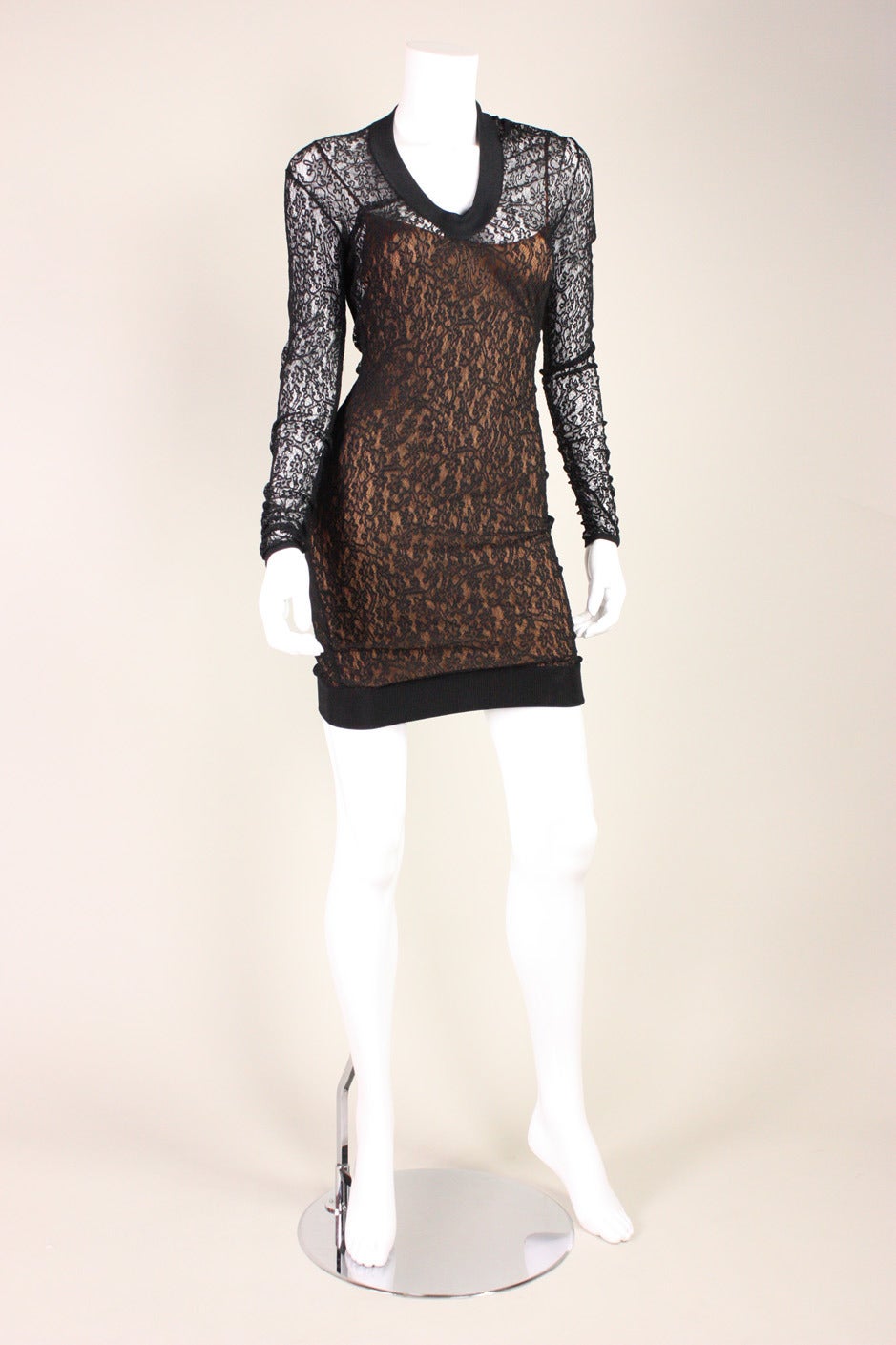 Vintage dress from Alaia dates to the 1990's and is made of transparent black stretch lace with a taupe-colored slip attached at the center front and side seams.  Ribbed trim around neckline, cuffs, and hem.  No closures.

No size label, but we