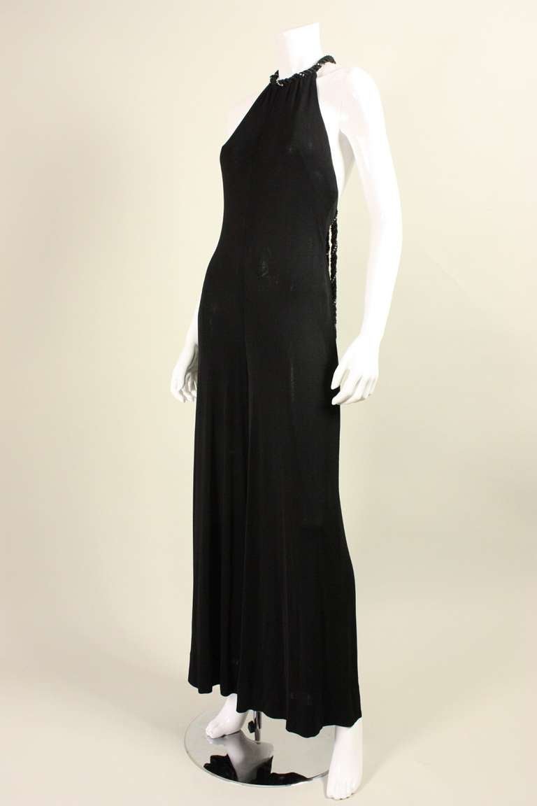 Vintage jumpsuit from Bob Mackie's early line, Elizabeth the First is made of black matte jersey.  It features a round neckline that is trimmed with twisted black braid and clear rhinestones.  This trim can either tie at center back neck or front