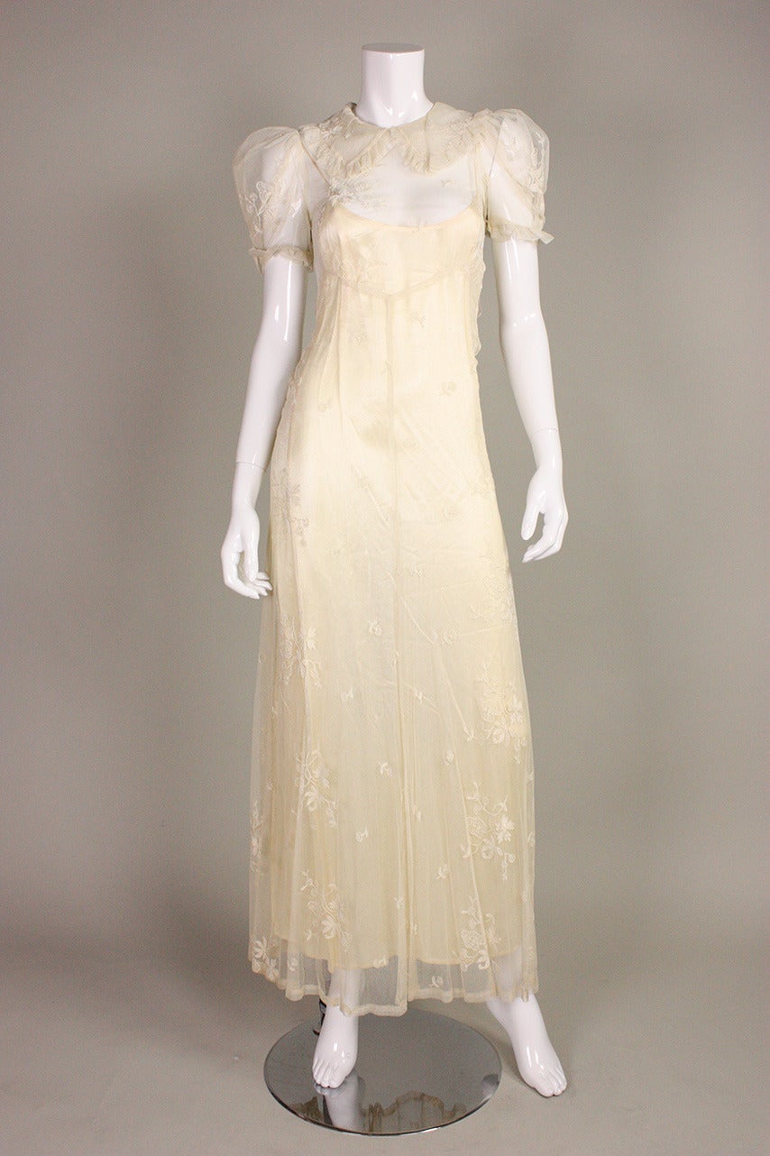 Vintage gown dates to the 1930's and is made of soft cream netting with embroidered floral sprays throughout.  Turn down rounded collar.  Voluminous short sleeves.  Center back keyhole opening at neckline. Hook and eye closure at back neck.  Unlined