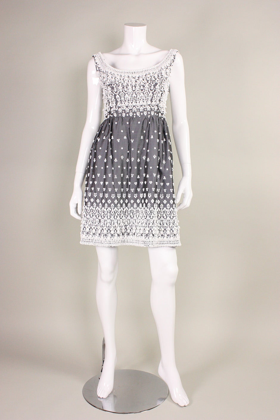 Vintage dress from "Gaby Espana" dates to the 1960's and is made of gray silk shantung.  It features white beading that is hand-sewn throughout.  Fitted bodice has scoop neck.  Above knee-length skirt is gathered all around waistband. 