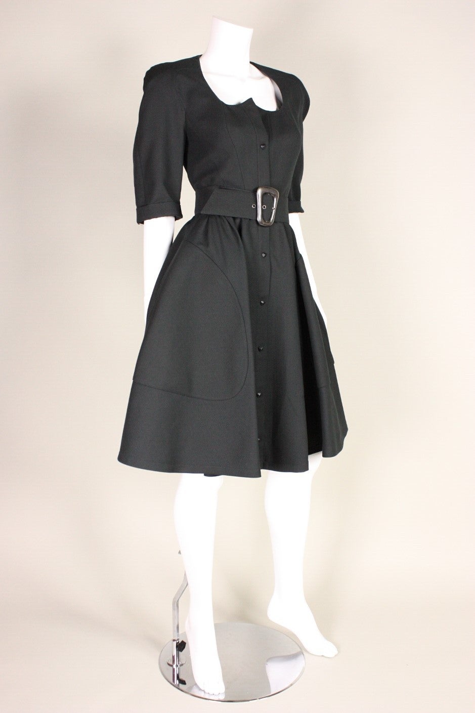 Vintage dress from Thierry Mugler dates to the 1990's and is made of textured black cotton.  Fitted bodice is shaped by curving vertical seams.  Elbow-length sleeves have rolled up cuffs.  Flounce skirt has gathering all around the waistband and hip