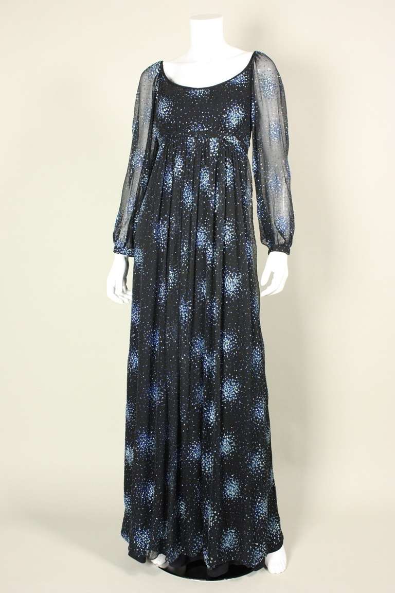 Elegant gown from Alfred Bosand dates to the 1970's and is made of black chiffon that is covered in groupings of blue and silver glitter.  Empire bodice has scooped neckline.   Long sleeves have snap cuffs and blouse slightly at wrists.  Lined