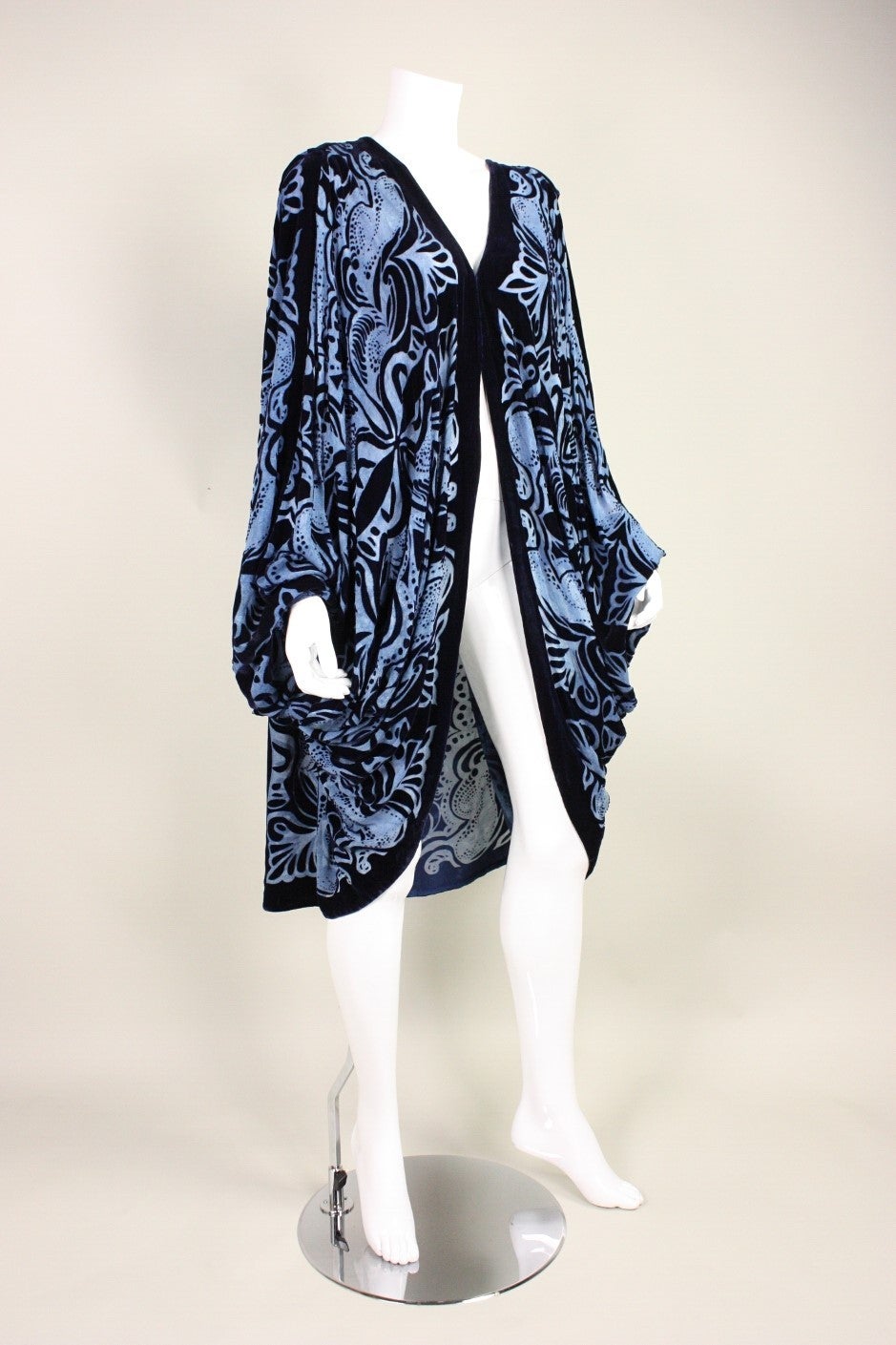 Vintage cocoon coat from Charles & Patricia Lester is made of navy velvet devore (burnout) in a scrolling pattern.  V-neck.  Two hook and eye closures at the center front bust may have been added later.  Snaps at wrists.  Unlined.

No size label. 