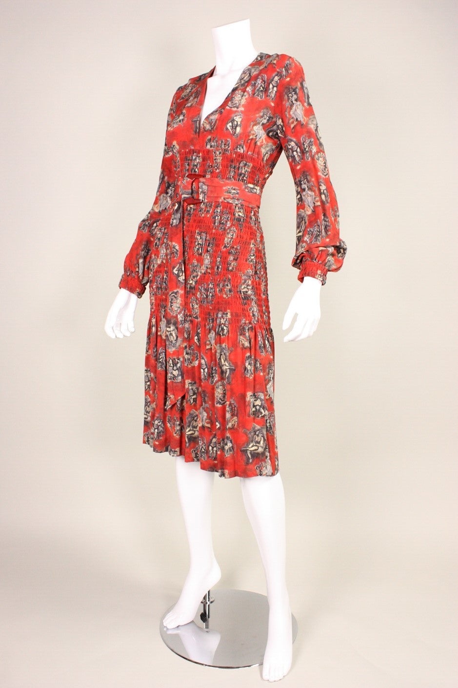 Cocktail dress from Jean Paul Gaultier is made of brick red silk with a print resembling the burlesque works of Toulouse Lautrec. Bodice has a deep v-neck. Ruched waist starts just below the bust and ends just beneath the buttocks.  Sleeve cuffs