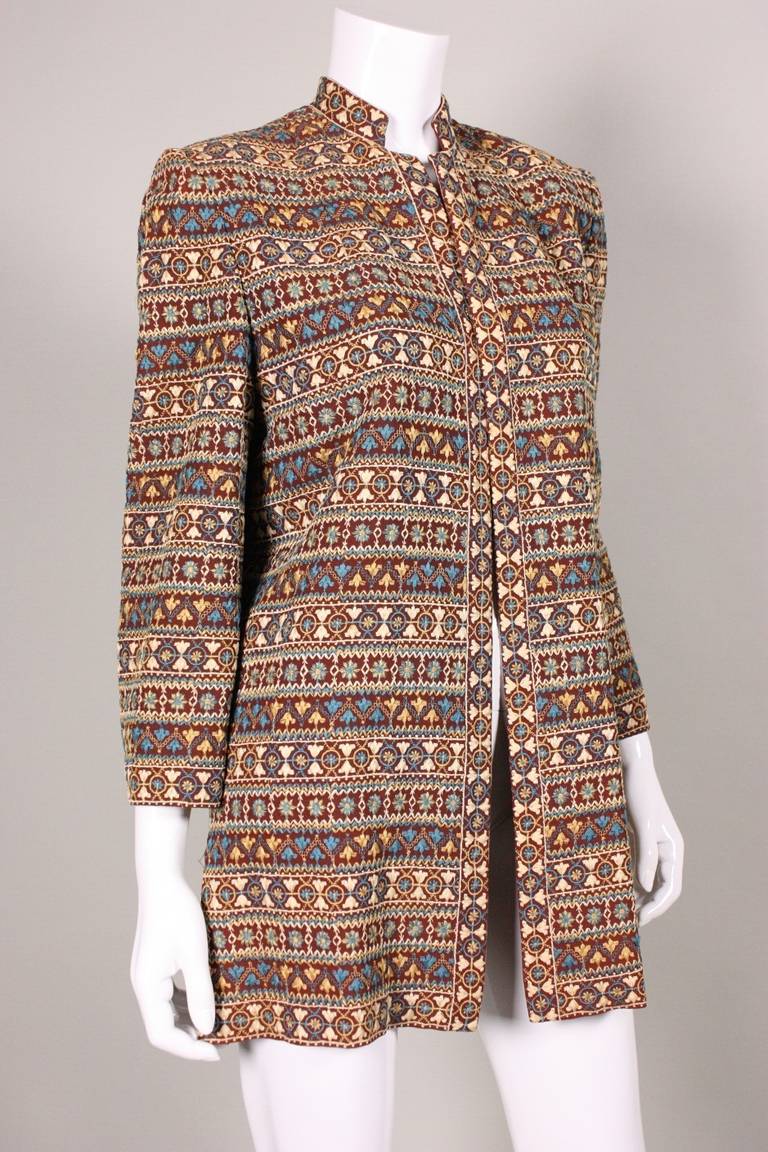 Fabulous jacket from Fred A. Block dates to the 1940's and is made of brown wool gabardine with cream, tan, blue, and brown hand embroidery in a geometric pattern.  Stand collar.  No closures.  Fully lined.  Shoulder pads.