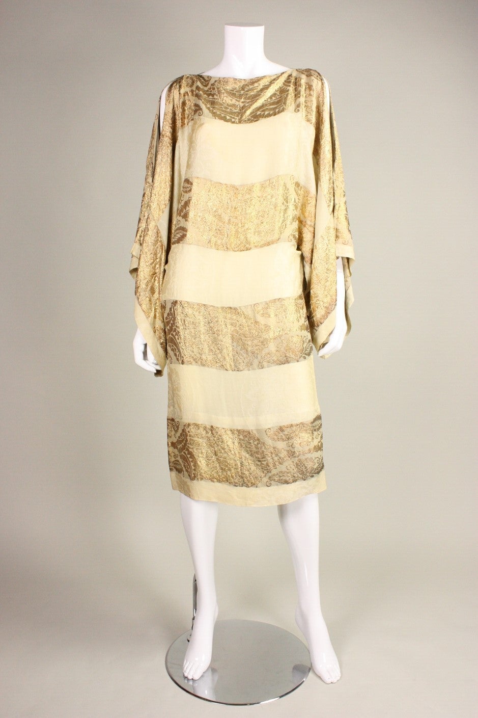 Vintage cocktail dress dates to the 1920's and is made of yellowish-green and gold lame jacquard silk fabric.  It is comprised of a simple, yet striking pattern with a bandeau neckline and extra wide sleeves with side slits.  Unlined. No