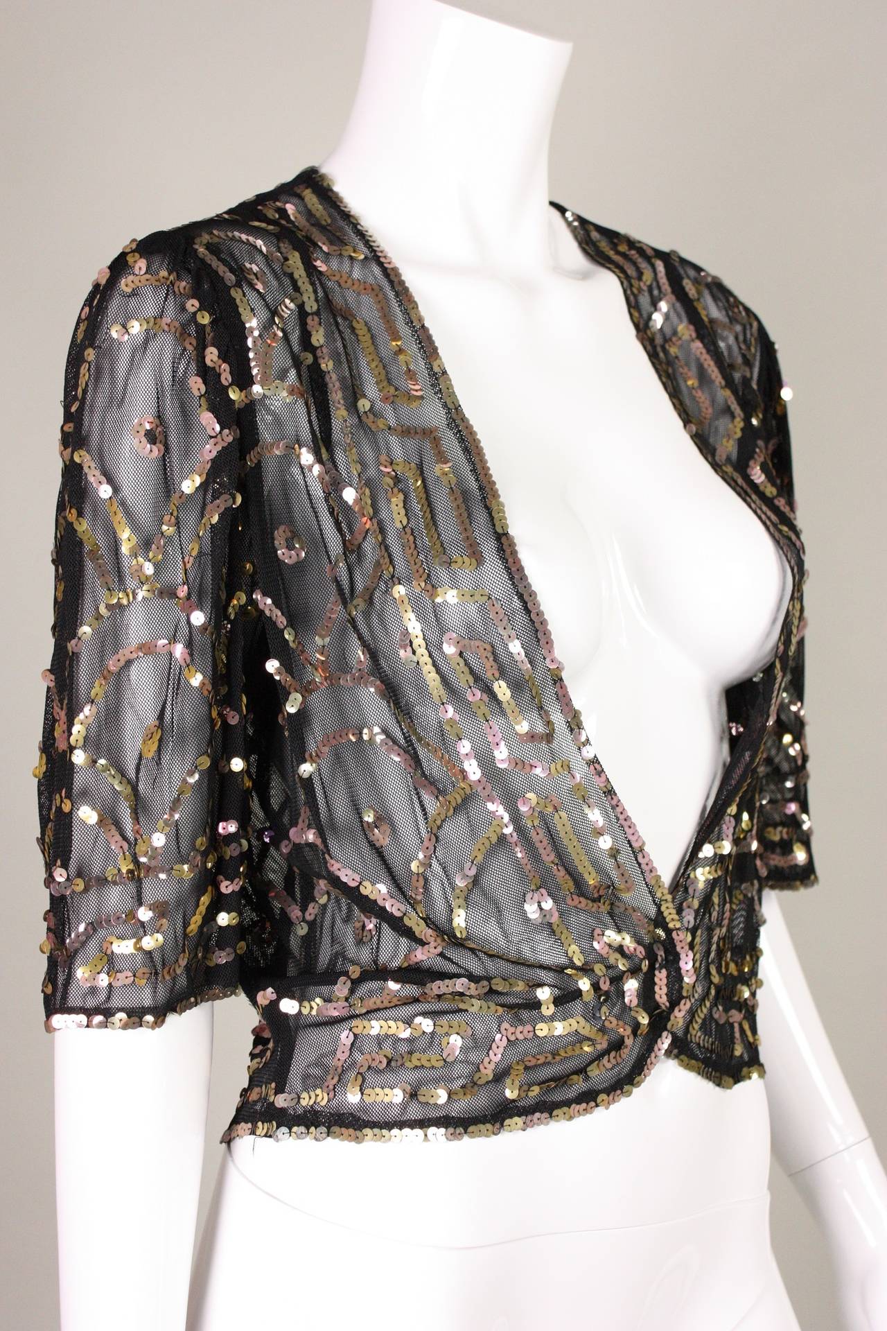 Vintage bolero dates to the 1930's and is made of soft black netting that is adorned with gold and copper colored sequins in a geometric pattern.  Short sleeves are gathered at shoulder seam.  Center front double snap closure at waist. 