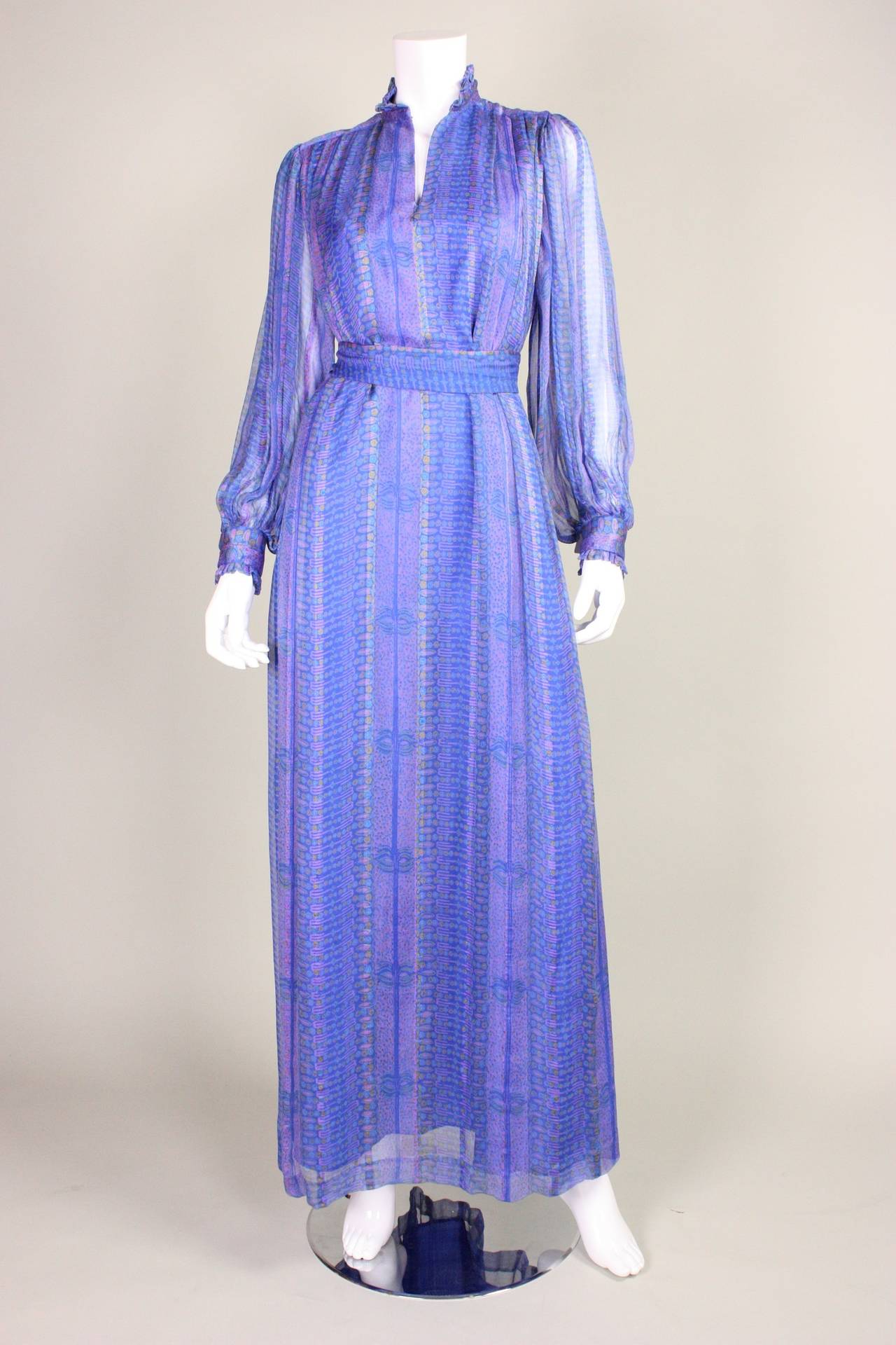 Vintage maxi dress from Raksha dates to the 1970's and is made of printed blue/purple silk chiffon.  Center front slit neck with hook and eye closure.  Ruffled stand collar.  Long sleeves button at the cuffs.  Lined except for in sleeves.  Center