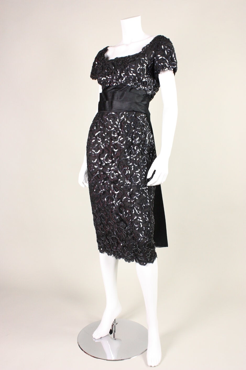 Vintage cocktail dress from Maxwell Shieff Beverly Hills is made of black lace with gunmetal gray sequins sewn on to echo the pattern of the lace.  Pleated black satin waistband.  Back train has gray silk on underside that compliments the color of