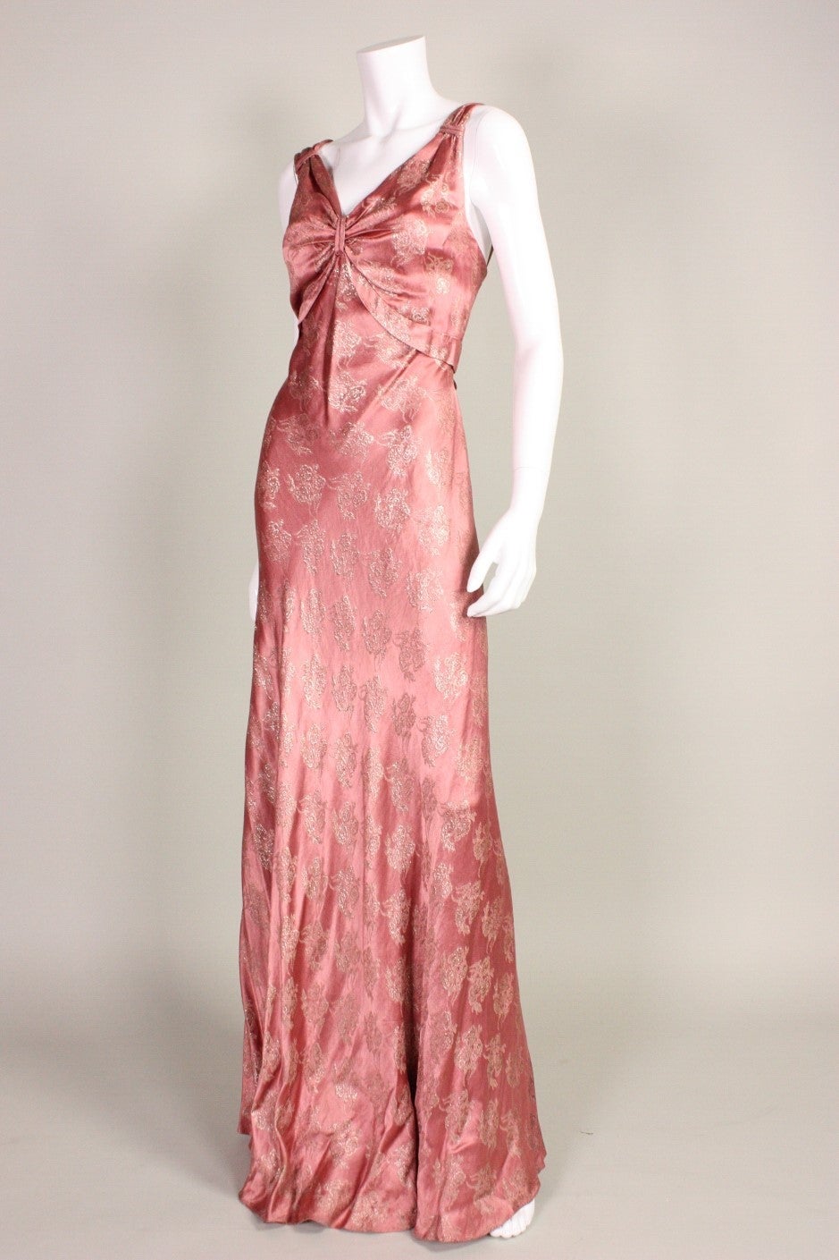 Vintage gown dates to the 1930's and is made of a beautiful mauve silk and lamé with a floral pattern.  V-neckline with gathering at the shoulders and center front bust.  Attached waistband starts at center bust and ties at the center back waist. 