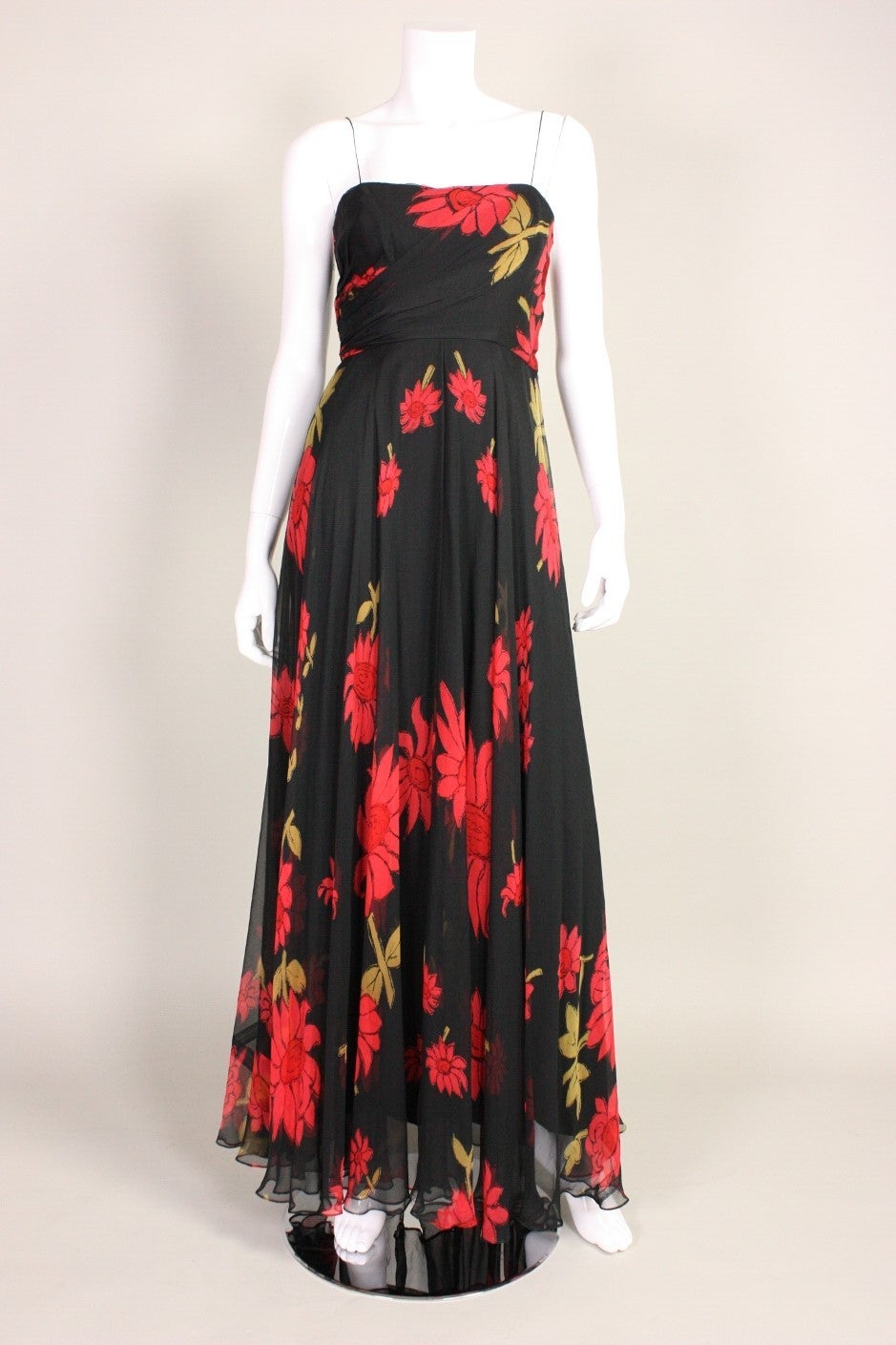 Mid-1950's gown with a 1930's feel.  Black silk chiffon with a large floral print in red and green.  Fitted bodice gathers diagonally at side waist.  Ankle length, bias cut skirt.  Built-in boned waist corset.  Spaghetti straps.  Side metal zip. 