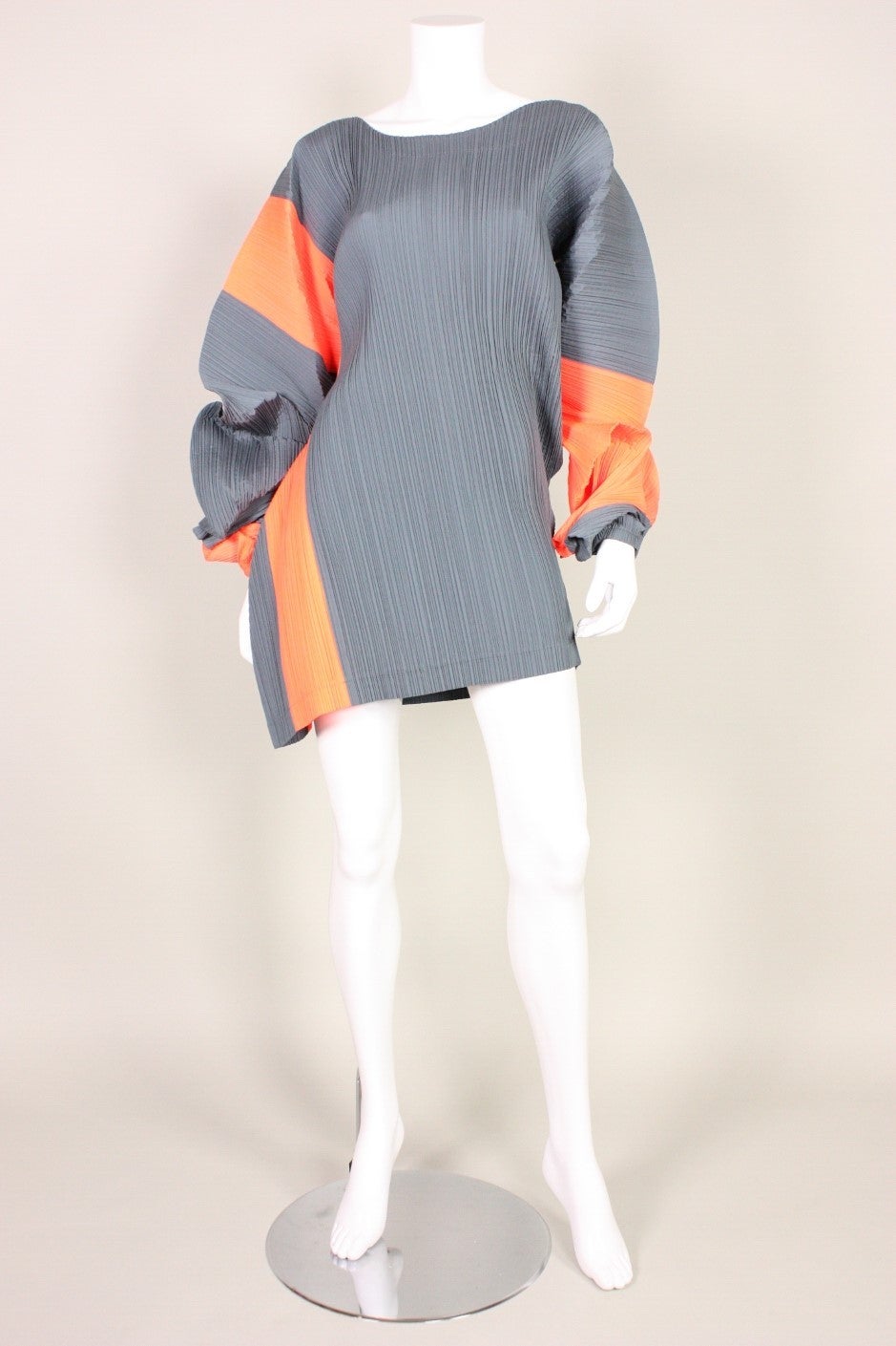 Issey Miyake gray and orange pleated mini dress dates to the early 1990's. Colorblocked with twisted voluminous 'paper lantern' sleeves.  Asymmetrical neckline.  Sewn using only one seam.  Unlined.  Please note, that the gray and orange came out