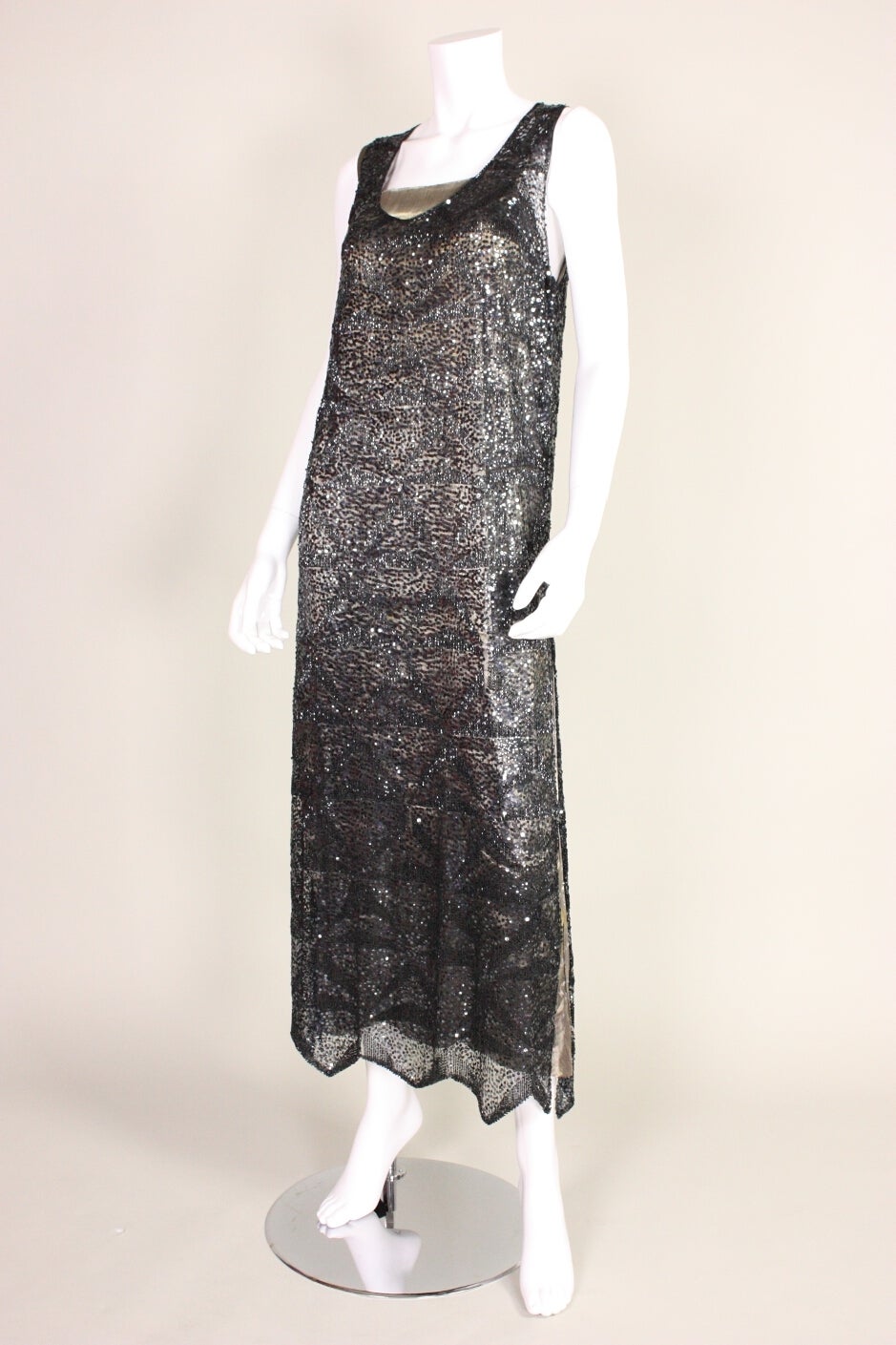 Vintage party dress dates to the 1920's during the Art Deco era.  It is made of black netting adorned with gunmetal gray small sequins and black bugle beads.  Gold lamé slip is exposed at neckline.  Zigzag hem.  Unlined.  Side snap closures.