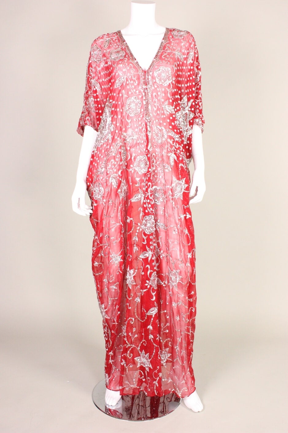 Vintage caftan dates to the 1970's and is made of red silk chiffon with allover silver sequined adornment and metallic silver embroidery.  It features a deep v-neck that is trimmed with sequins.  No closures.  Unlined.  Comes with a red silk that