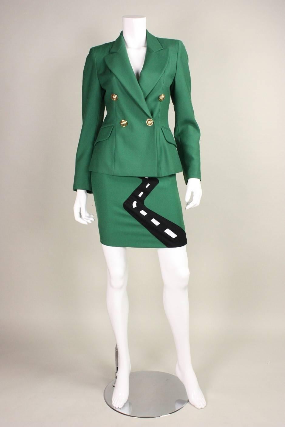 Vintage Moschino Cheap & Chic suit dates to the 1990's and is made of green wool with an appliqued landscape scene on the front skirt.  Blazer is double-breasted with gold-toned buttons.  Straight skirt has zippered closure.  Both pieces are lined.
