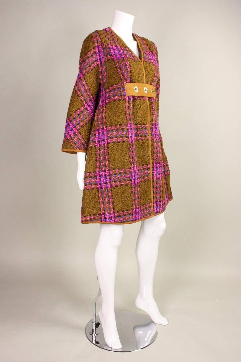 Iconic coat from Bonnie Cashin for Sills is made of olive green wool boucle with pink, fuchsia, purple, and black yarn woven in an extra large check pattern.  Suede trim and front waistband.  Three turn metal closures at center front.  Unlined. Hip