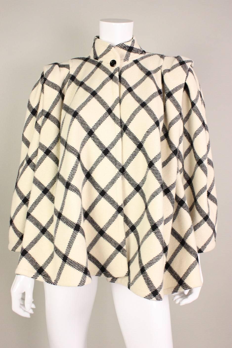 Vintage short coat from Ungaro dates to the 1980's and is made of a heavy cream wool with a large black checkered pattern.  Stand collar.  Single center front button closure at neckline.  Unlined.

Labeled a size 6.