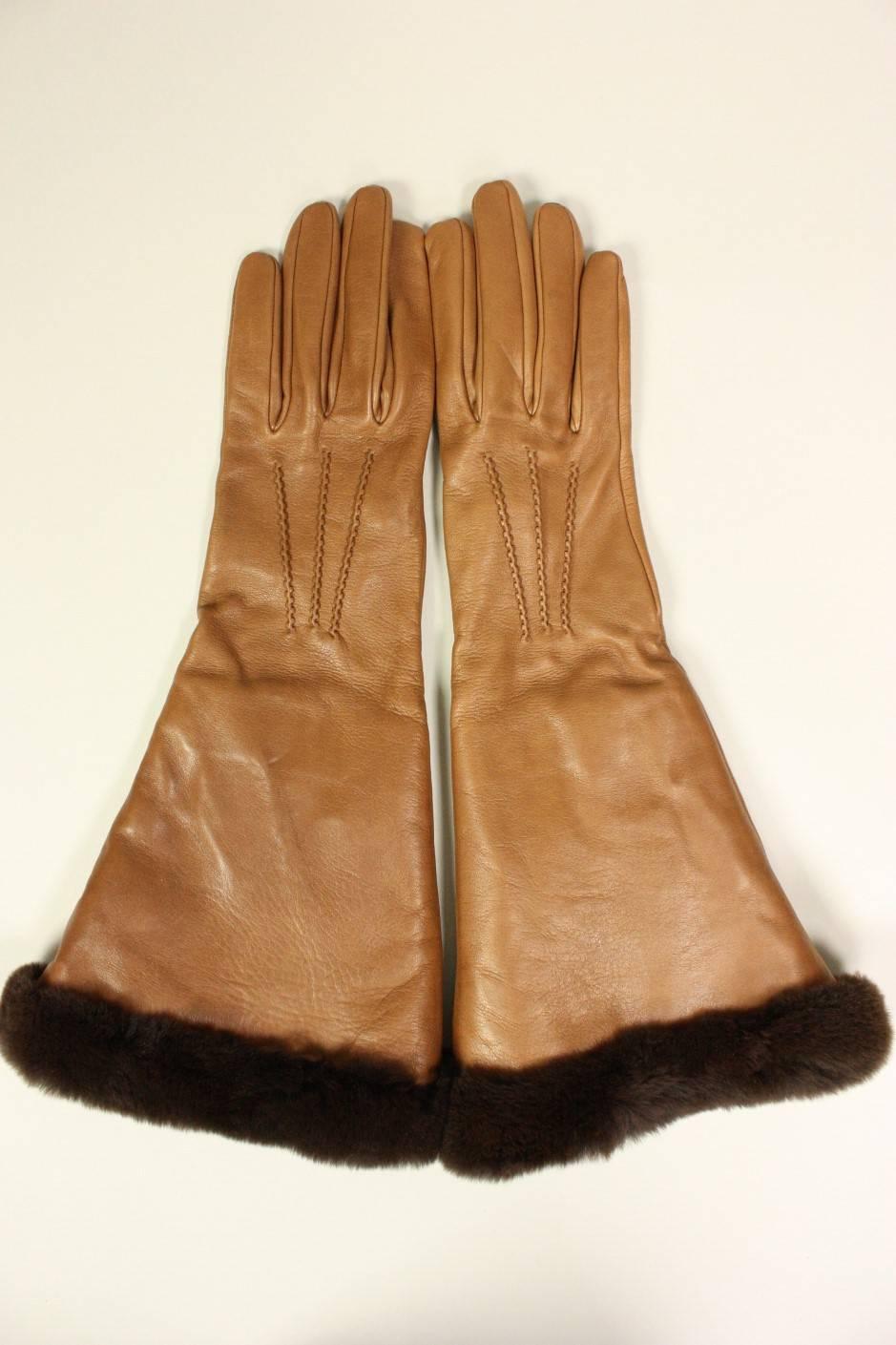 Gauntlet gloves from Hermes are made of buttery-soft, caramel-colored lambskin.  Contrasting dark brown fur trim extends from the glove opening to wrist. Light gray silk jersey lining.  Labeled size 7.