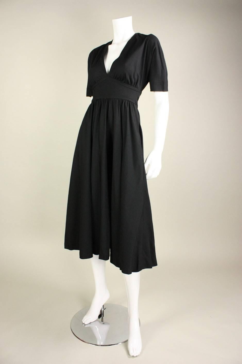 Vintage little black dress from Halston is made of silk dupioni and dates to the 1970's.  Bodice features a deep v-neck, doleman sleeves, and is fitted from the underbust to the waist.  Full skirt is gathered all around waistband.  Two ties at the