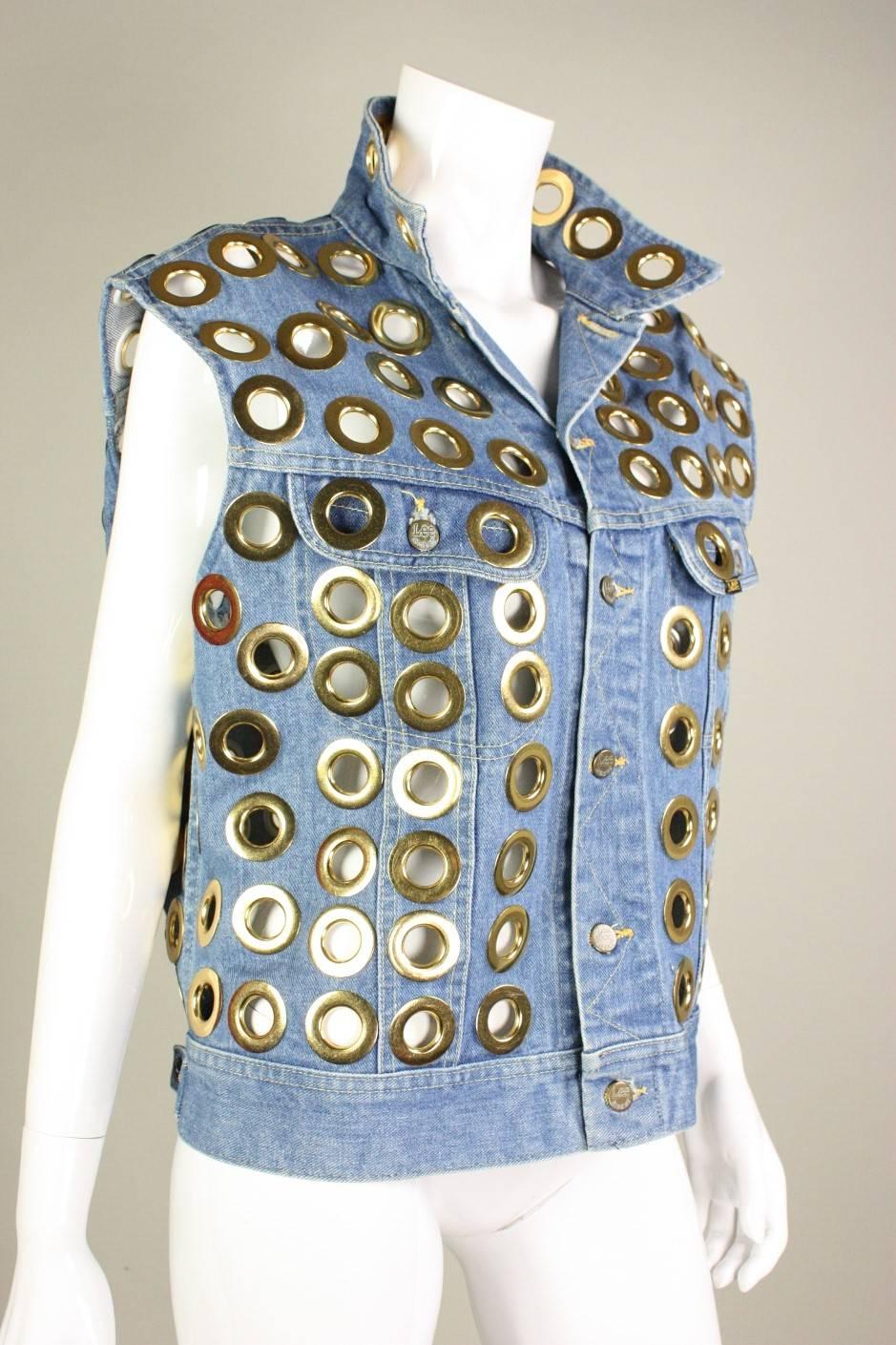 Vintage vest from Fred Hayman dates to the 1980's and was repurposed from a denim vest from Lee.  It is covered with extra large gold-toned grommets throughout.  Unlined.  Center front button closure. 

Measurements-
Chest: 48