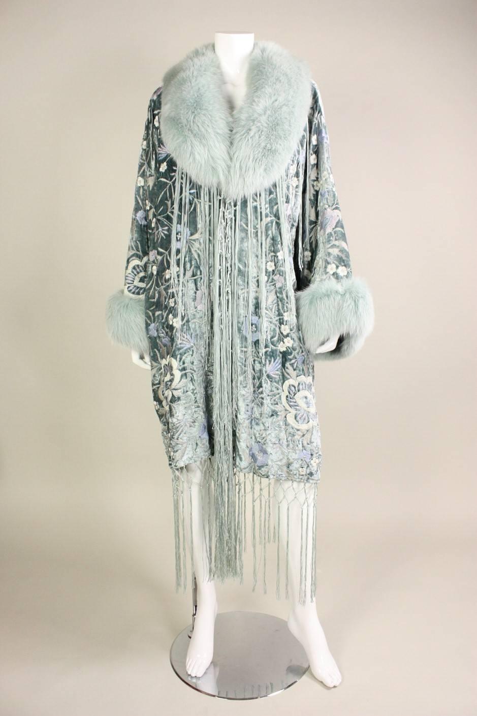 Vintage coat from Adrienne Landau dates to the 1990's and retailed at Bergdorf Goodman.  It is made of light blue velvet with floral embroidery in pastel shades.  Norwegian fox fur trim has been dyed an icy blue.   Knotted fringe trim.  Fully lined.