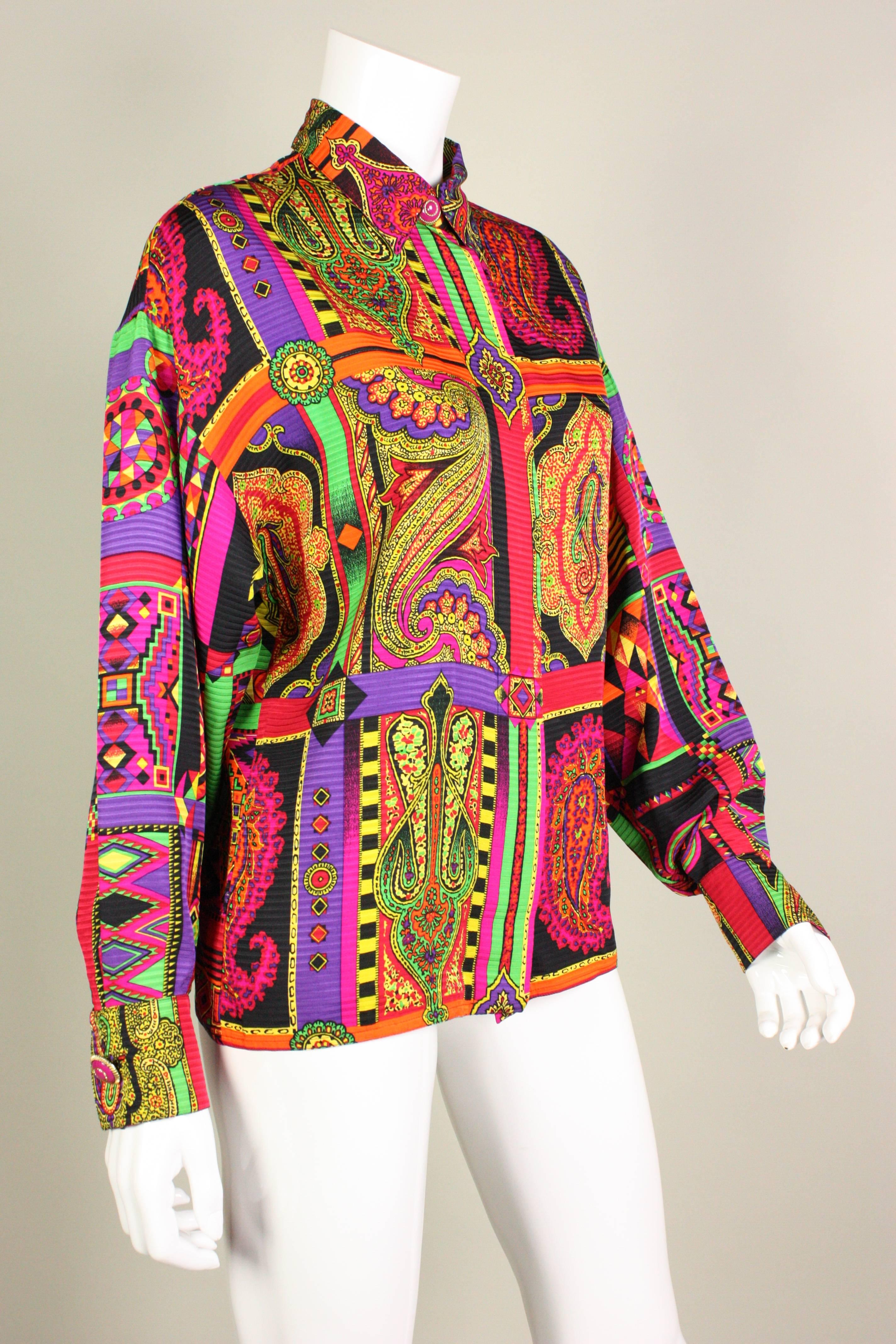 Brightly-colored blouse from Versace dates to the 1990's and is made of silk with a bold print.  Turn down collar.  Dark pink enamel buttons at neckline and cuffs.  Center front covered button closure.  Unlined.  

Labeled size