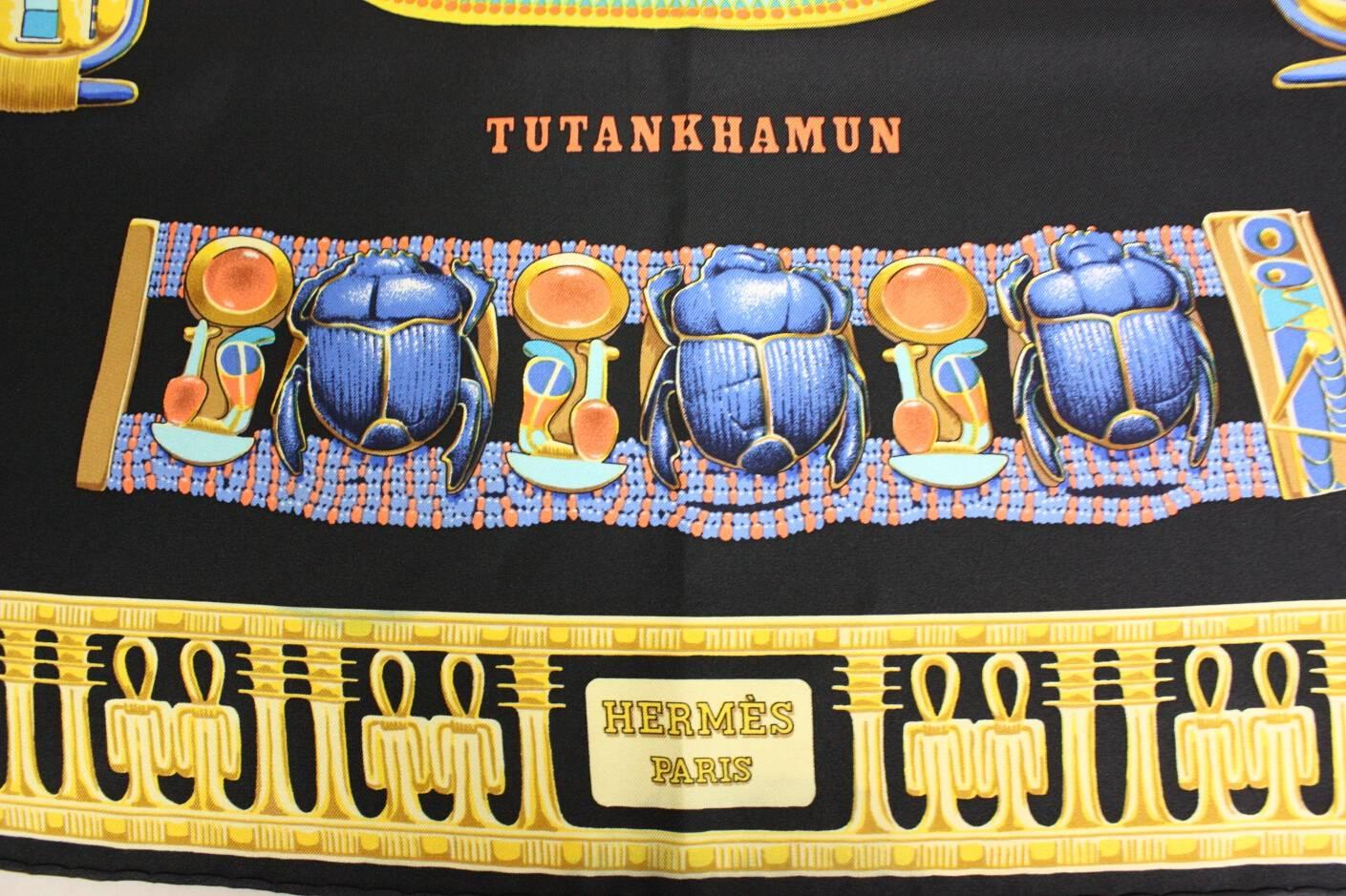 Tutankhamun scarf from Hermes is made of navy silk twill.  It was designed by Vladimir Rybaltchenko and issued in 1994 (although this could be a reprint).  Hand-rolled edges.  

It measures approx. 35