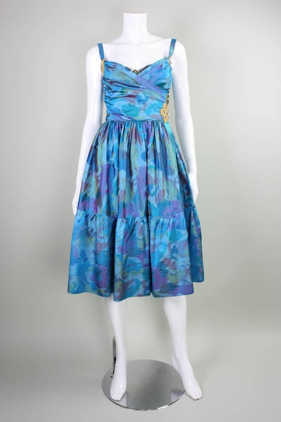 Vintage dress from Tracy Feith dates to the 1990's and is made of silk with an ikat weave in tones of blue, green, and purple.  Fitted bodice has ruched crisscross neckline with a black lace insert at center front.  Flared skirt is gathered all