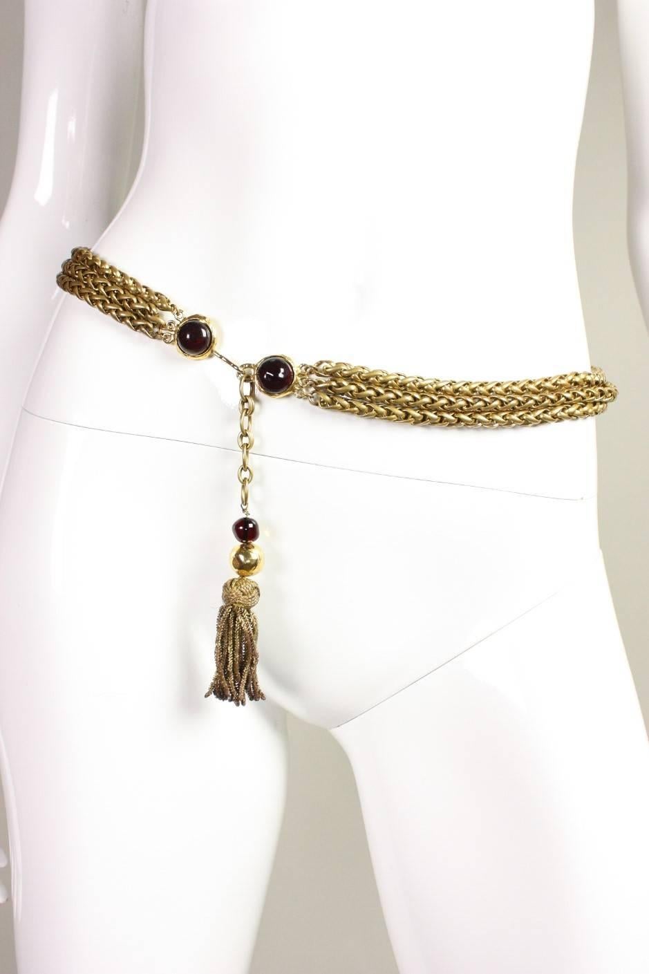 Vintage belt from Chanel likely dates to the 1980's and is made of gold-toned metal with an antiqued finish.  Three strands of dense chain.  Deep red gripoix details.  Chain is finished with a gold bullion tassel.  

Waist length- 29 1/2