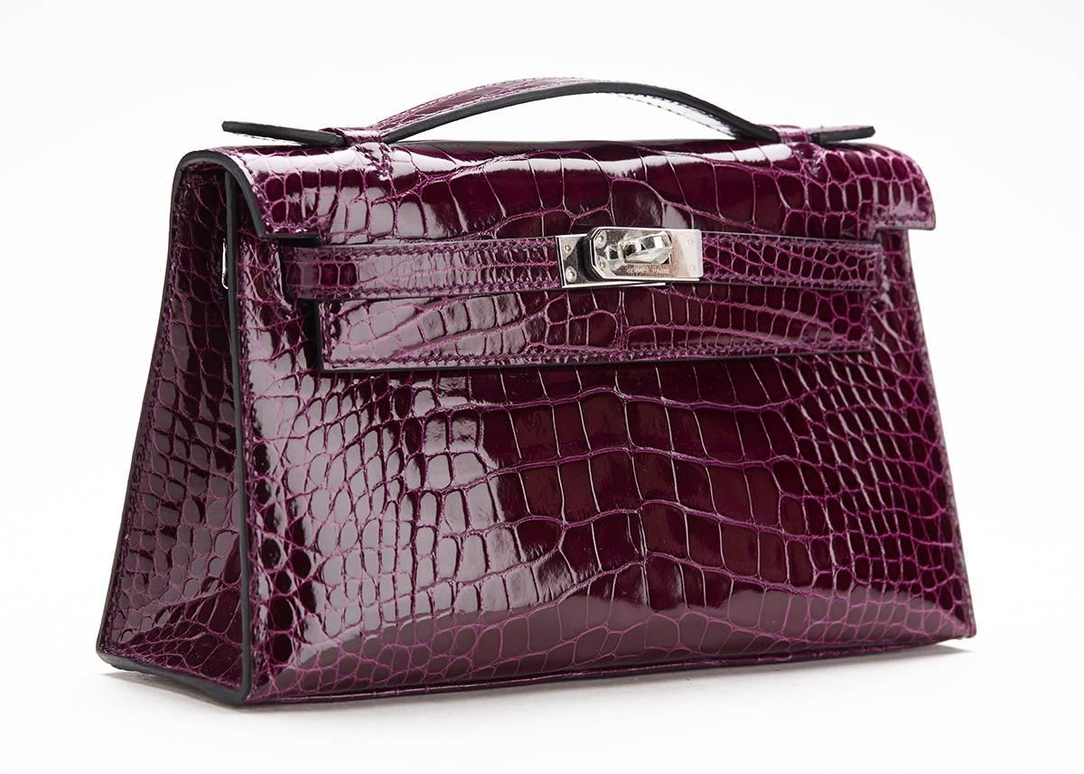 This ladies Hermès Kelly Pochette is primarily made from Cassis shiny alligator complimented by palladium hardware. This bag is in unworn condition accompanied by Hermès box, dust bag, care cards. 2015. Our  reference is CB040 should you need to