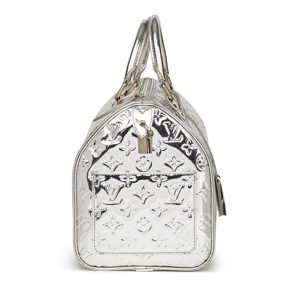 LOUIS VUITTON
Silver Monogram Miroir Vinyl Speedy 35

Reference: HB2265
Serial Number: SP1006
Age (Circa): 2006
Accompanied By: Lock, Keys. Clochette, Care Booklet
Authenticity Details: Date Stamp (Made in France)
Gender: Ladies
Type: Tote

Colour: