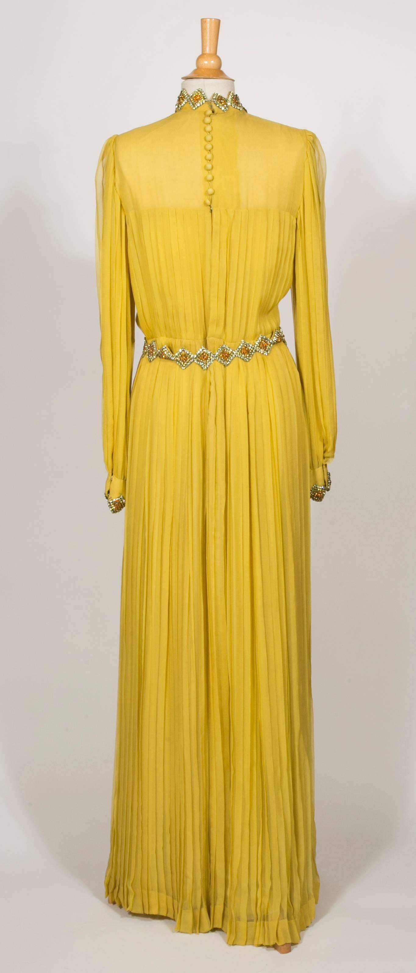 The neckline and the wrists are embroidered With Yellow ,Gold,and Cognac color strass in the shape diamond.
The belt takes back the same motive and is 75cm lenght .
The fabric is a Silk Chiffon and the dress and the sleeves are completely pleated