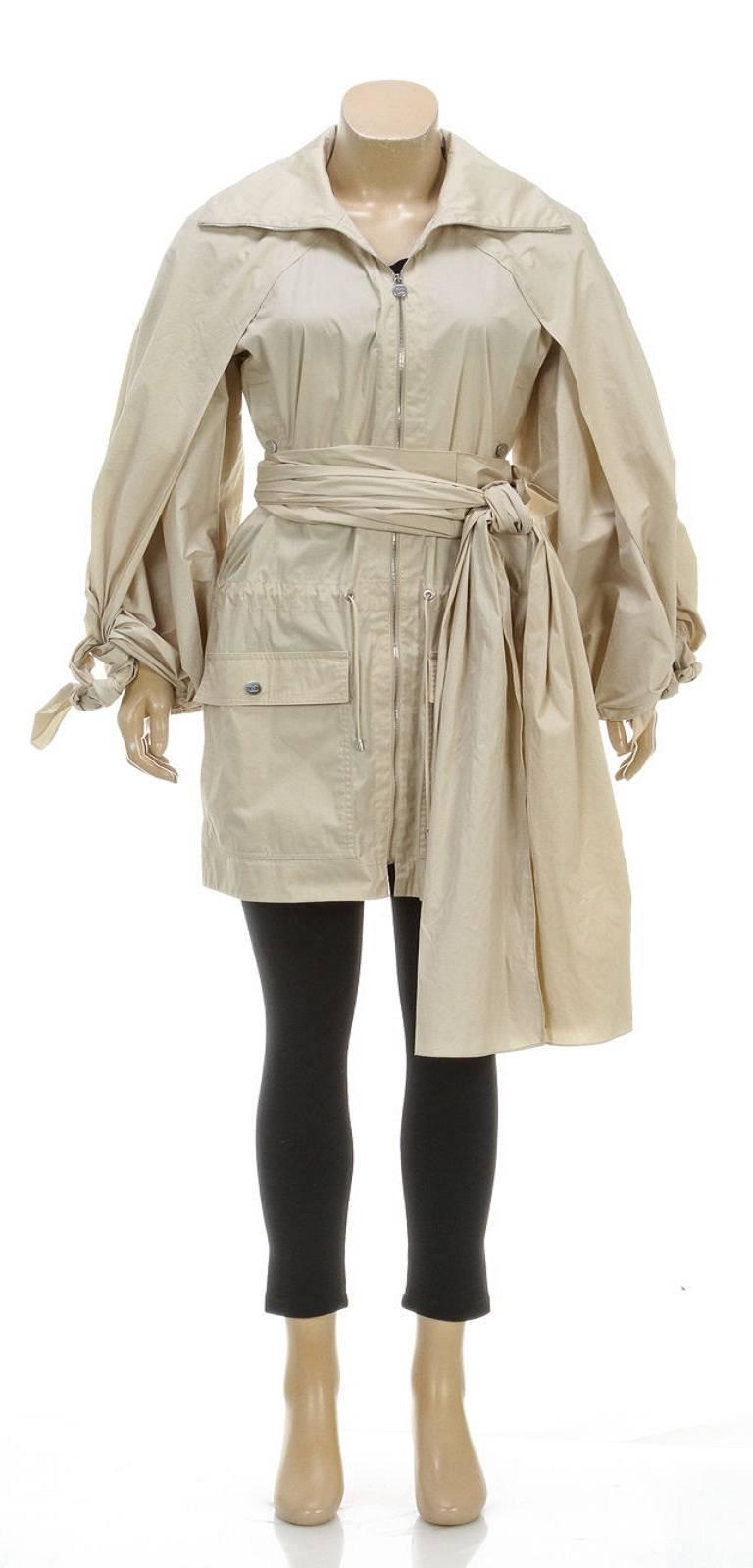 Keep it covered in this fantastic coat from Chanel! This beige jacket contains a construction of cotton and nylon as it falls in a long hemline, zipping up the front. Four pockets snap closed in the front while a drawstring lies inside the waist for