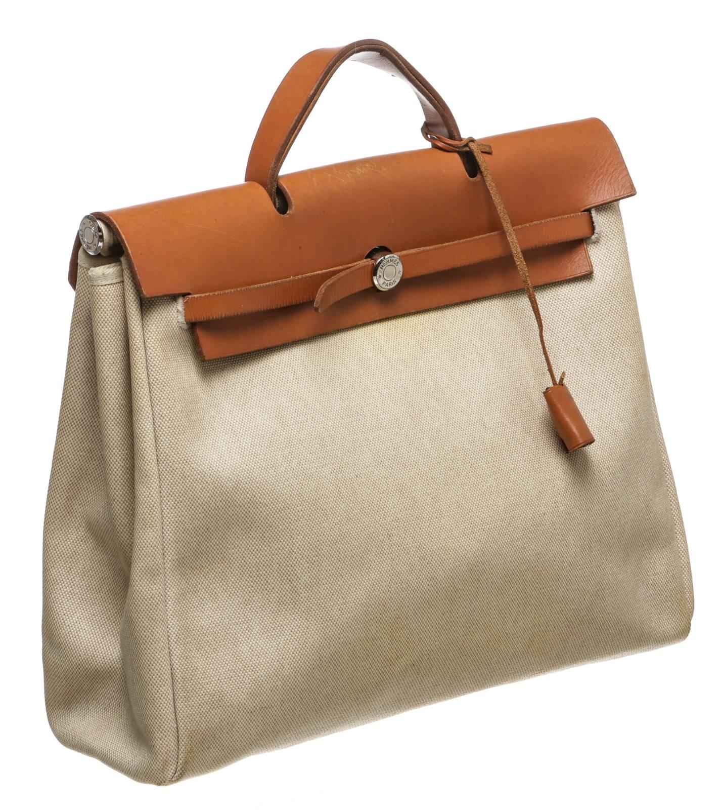 This versatile and stunning bag from Hermes offers you a go-to item for multiple occasions! It comes in a tan canvas with tan leather contrast as it closes off with a flap over the top. The interior contains a simple and open design for the