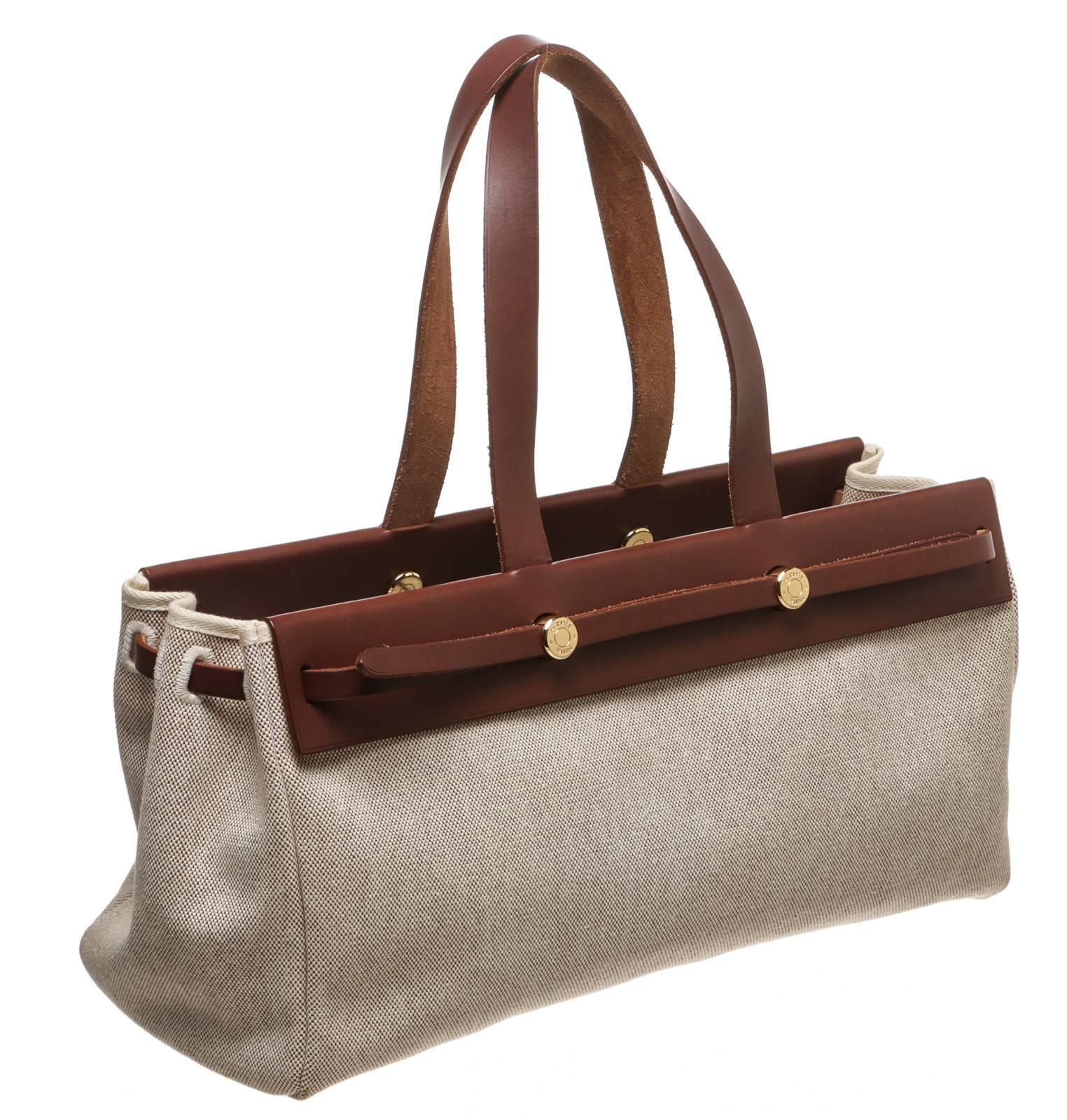 This versatile and stunning bag from Hermes offers you a go-to item for multiple occasions! It comes in a tan canvas with brown leather contrast as it closes off with a flap over the top. The interior contains a simple and open design for the