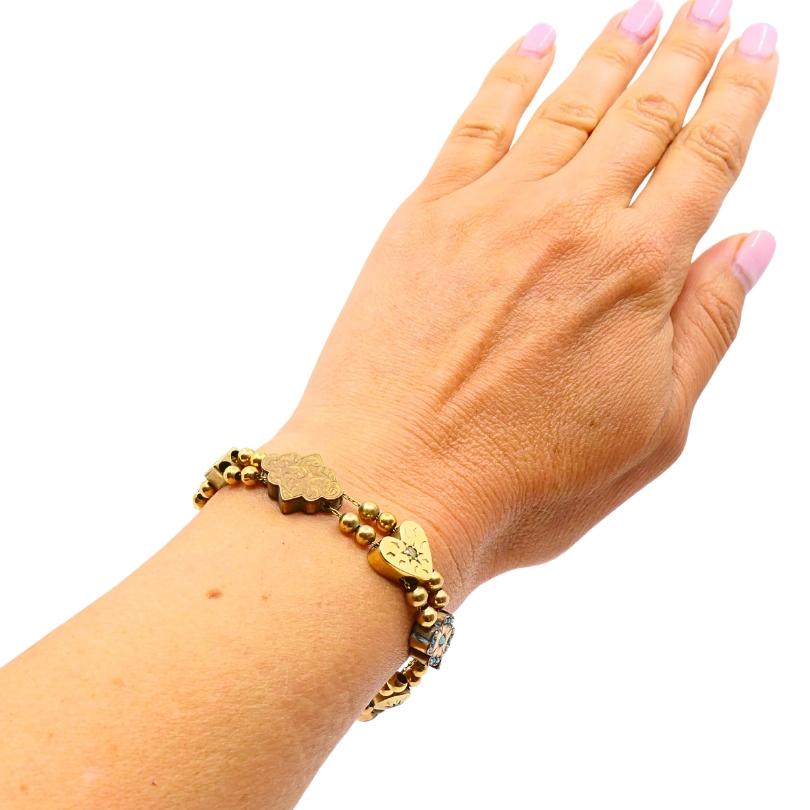 Bracelet coulissant en or 14k antique présentant un mélange éclectique de formes, de textures et de finitions. Le bracelet est composé de doubles rangs de perles dorées, enfilées avec des charmes à glissière individuels. Chaque lame est unique :