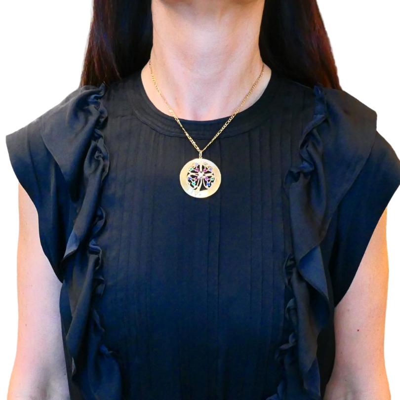 Questa splendida collana in oro 14k è caratterizzata da un ciondolo a forma di trifoglio ornato da vibranti pietre preziose. Il ciondolo è  realizzato in un classico design rotondo, evidenziato da un delicato motivo a trifoglio al centro. Ogni