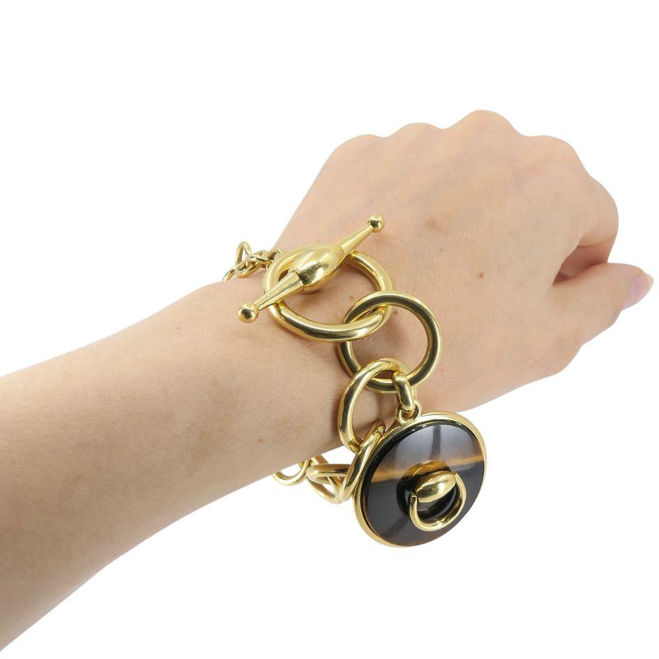 Questo bracciale Gucci ha un design audace e scultoreo, che mette in mostra l'equilibrio caratteristico del marchio tra eleganza e motivi di ispirazione equestre. Realizzato in ricco oro giallo 18 carati, il bracciale presenta maglie circolari