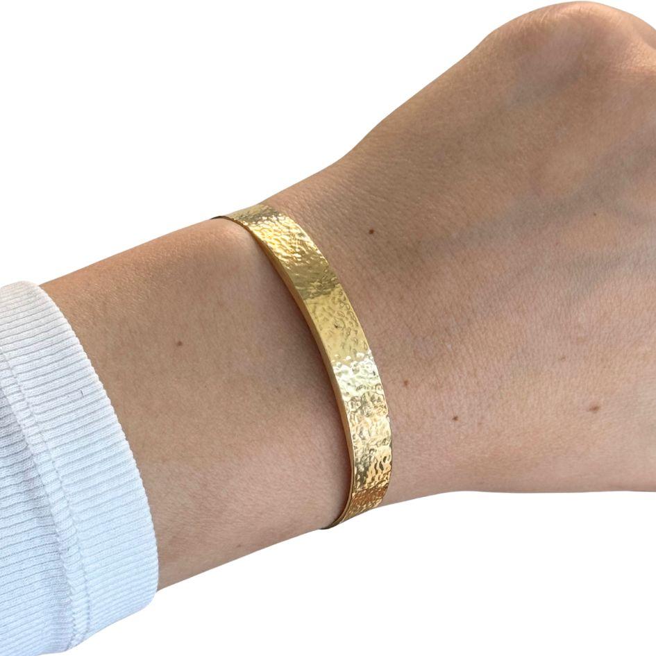 Ce bracelet manchette vintage est réalisé en or jaune 18k et présente une finition martelée à la texture et à la profondeur subtiles. Le bracelet mesure 6,75