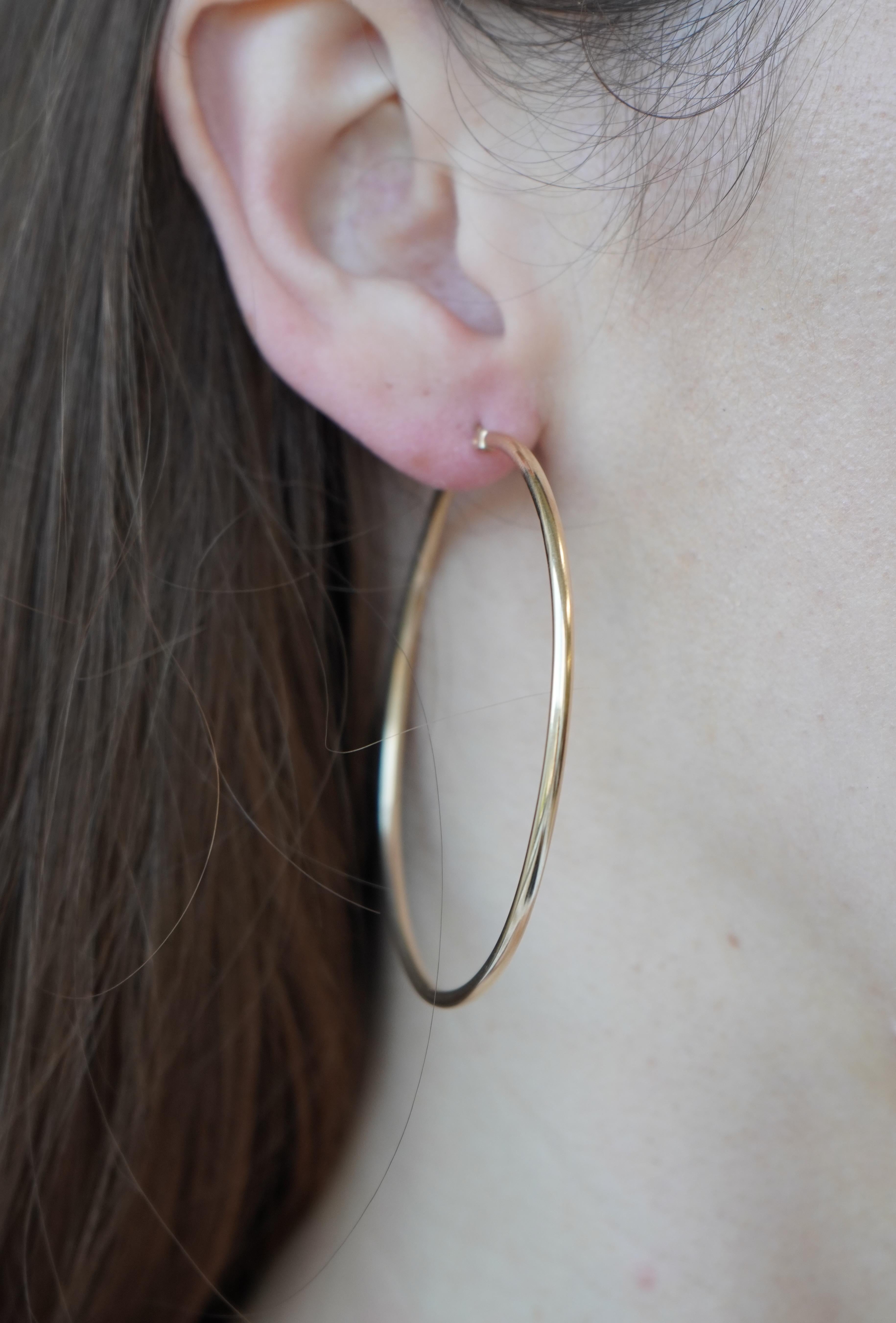 Ces grandes boucles d'oreilles en or jaune 14k présentent une silhouette ronde intemporelle à la finition épurée et minimaliste. Mesurant 2 1/4 pouces de diamètre, elles offrent un look audacieux mais léger, idéal pour le quotidien ou les occasions