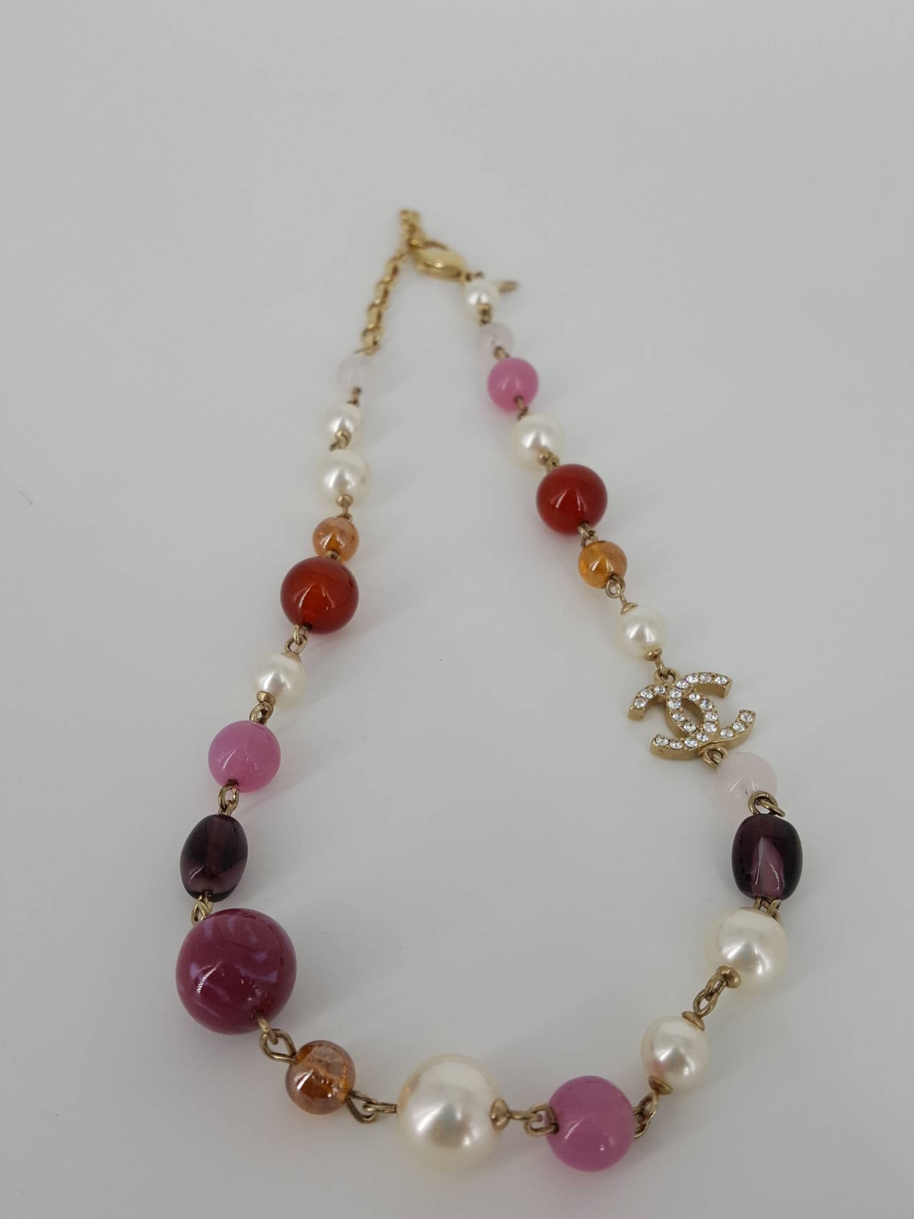 Offered for sale is this CHANEL Choker necklace with a lovely combination of glass beads and pearls with a double sided Rhinestone CC which lays on the one side.  The glass beads resemble semi precious quartz, rose quarts, amethyst, carnelian, and