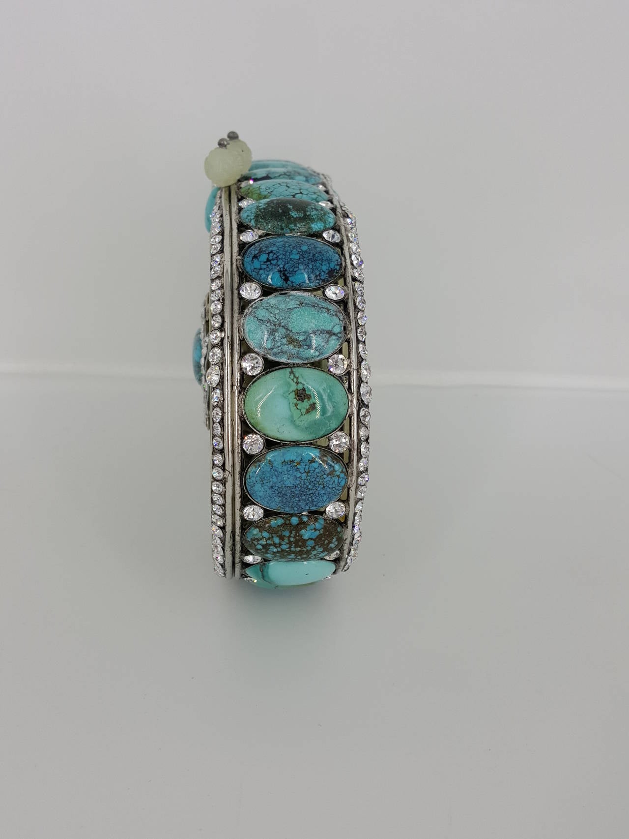 Offered for sale is this rare minaudiere by IRADJ MOINI.  This gorgeous piece has large carved jade on the front and back with a large cabochon turquoise stone in the center accented with Swarovski crystal and silver trim.  The sides and the bottom