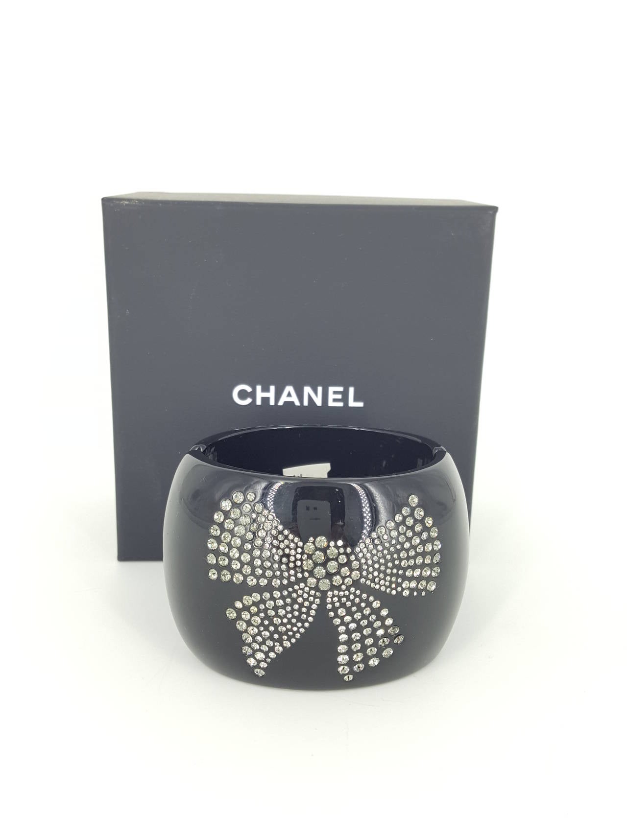 Offered for sale is this outstanding double sided wide hinged cuff bracelet by CHANEL from 2010.
Amazing in black lucite with a rhinestone CC on one side and rhinestone Bow on the other.  This large bracelet is 2 1/4