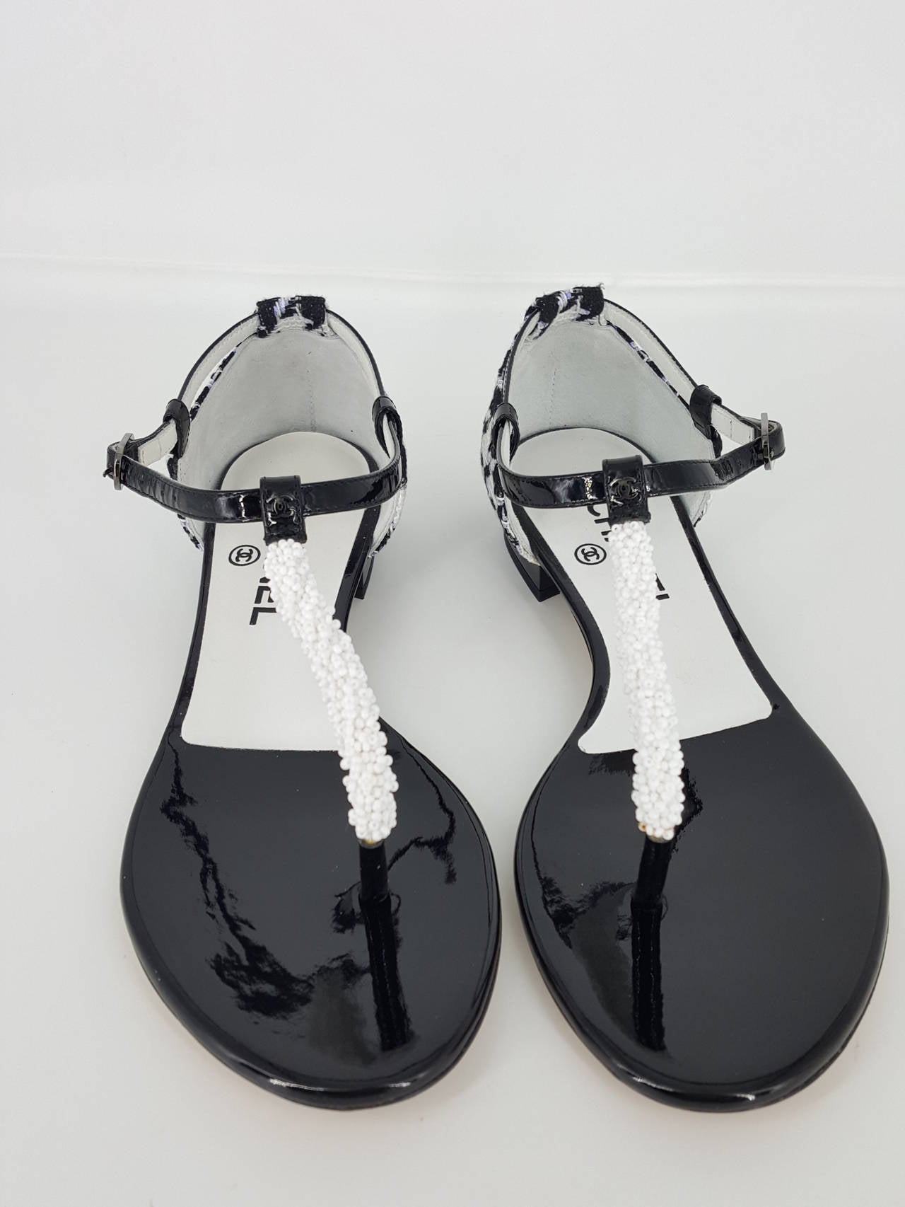 Offered for sale is a lovely pair of CHANEL Sandals from 2012 in Patent leather and black and white boucle highlighted by a lavender thread which almost glows.  The front is accented with white beads which almost resemble seed pearls.  These have a