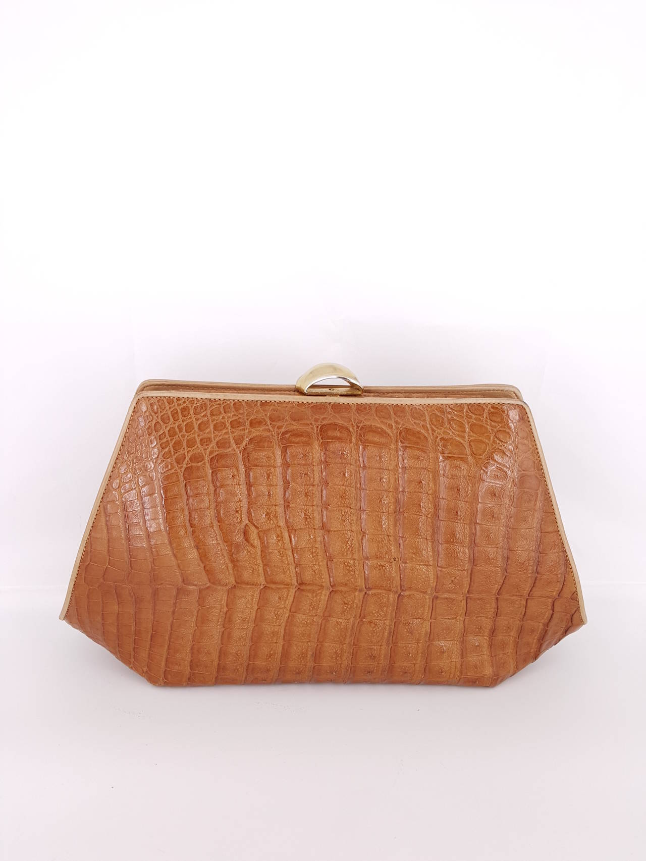 Offered for sale is this large vintage Donna Karan of New York Caiman crocodile clutch in a beautiful rich golden beige color. The outside edges are trimmed in a light tan leather.  This clutch is in exceptional condition and very rare.  It has a