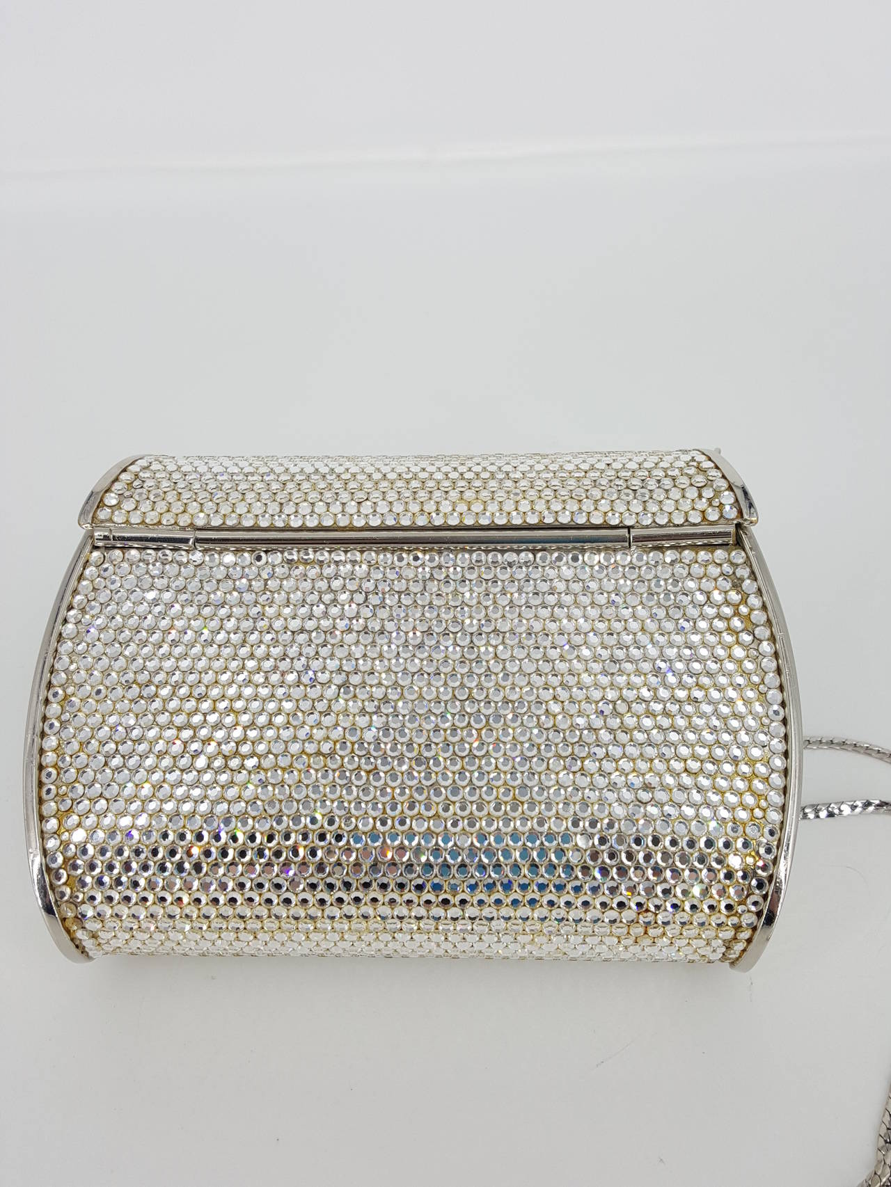 Offered for sale is this lovely Judith Leiber evening bag or minaudiere.  It is completely covered with clear crystals and has silver hardware and 20