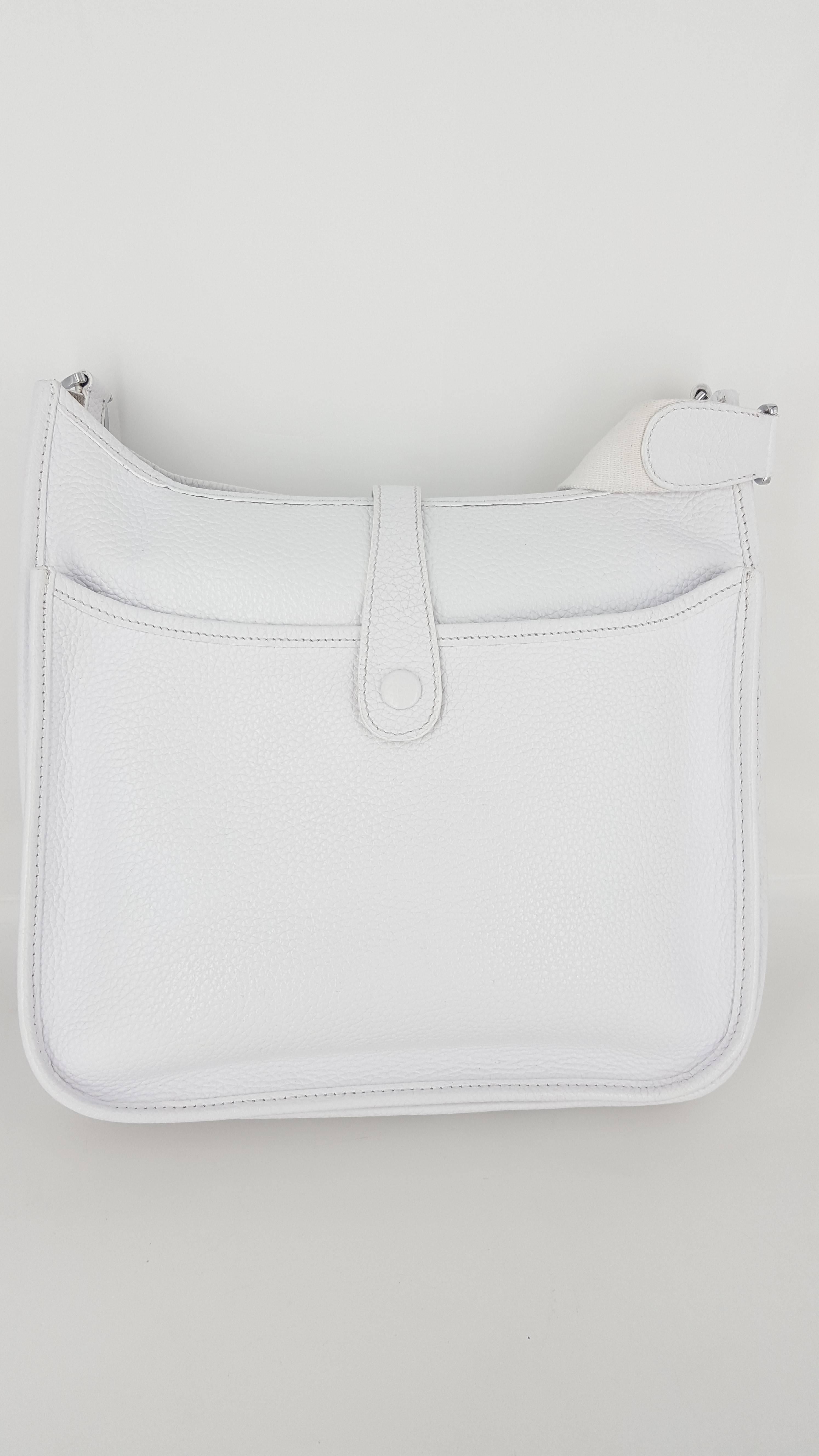 Offered for sale is a lovely Hermes Evelyne III PM in bright white with palladium hardware.  This is a nice size cross body bag with adjustable fabric strap.
The front of the bag has the well known perforated H and the rear of bag has a large 11
