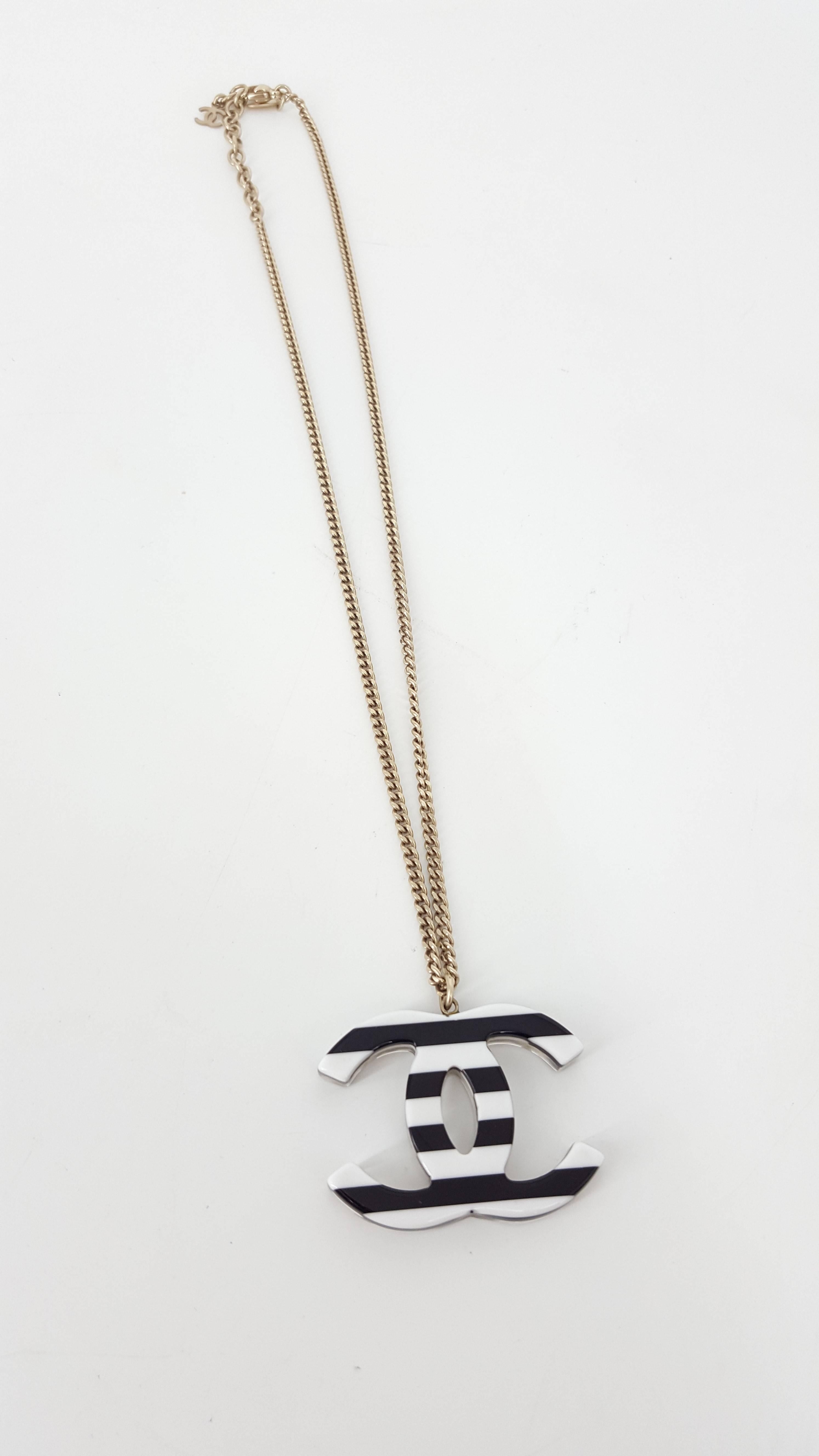 Offered for sale is this lovely Chanel necklace which is double sided in black and white and is 2006.  The one side has mini icons like shoe, camellia, cologne, high heel and tiny pearls encased in clear Lucite.  The other side is black and white
