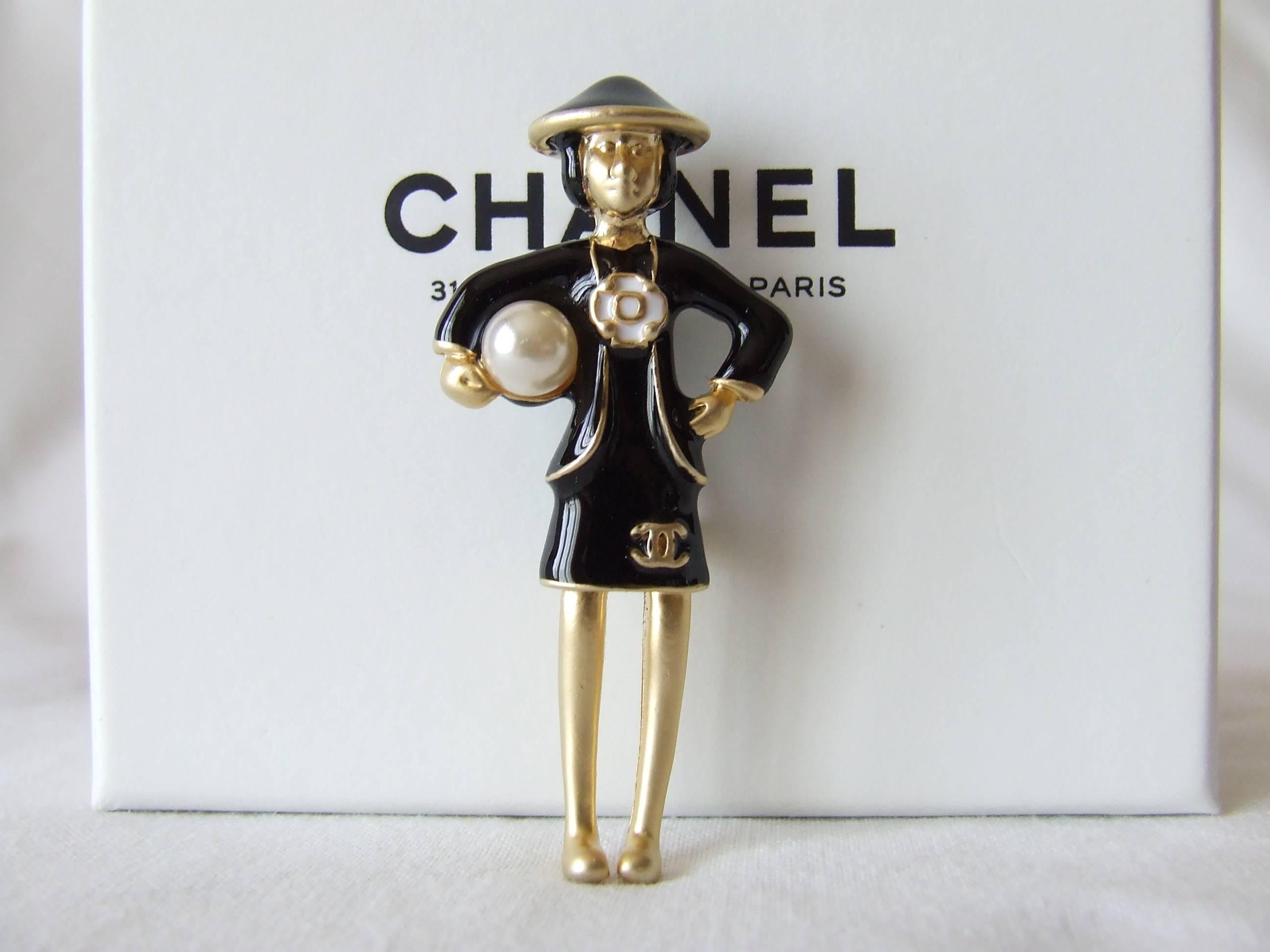 Beautiful and Rare authentic CHANEL Brooch

Made of golden Metal, dress and hat in black Enamel

Represents Coco Chanel in her black dress, holding a pearl under her right arm

Camelia in the middle, and cc logo at the bottom of the